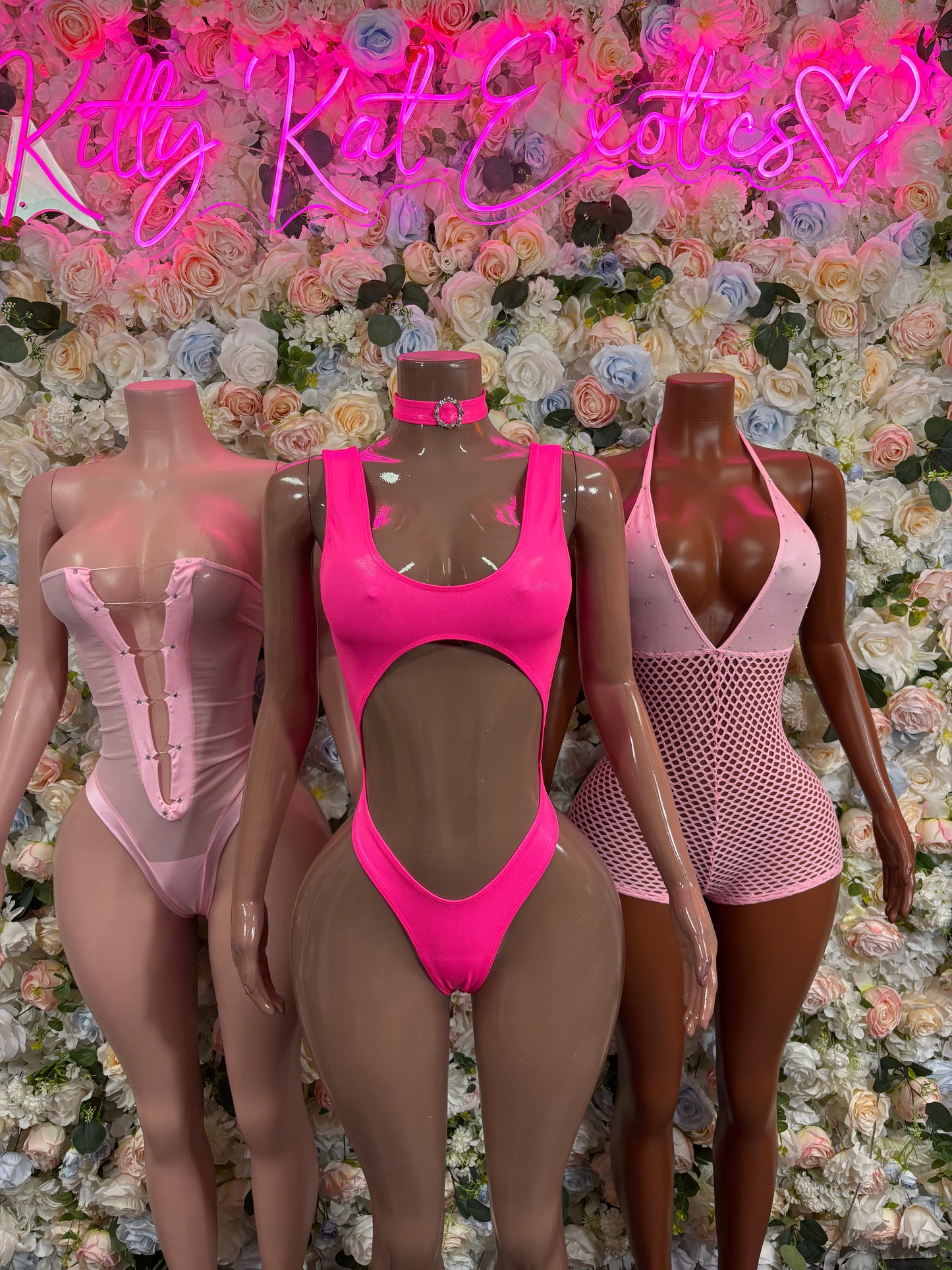 Pink one-piece bodysuits on three mannequins, hot pink scoop front and pale pink styles
