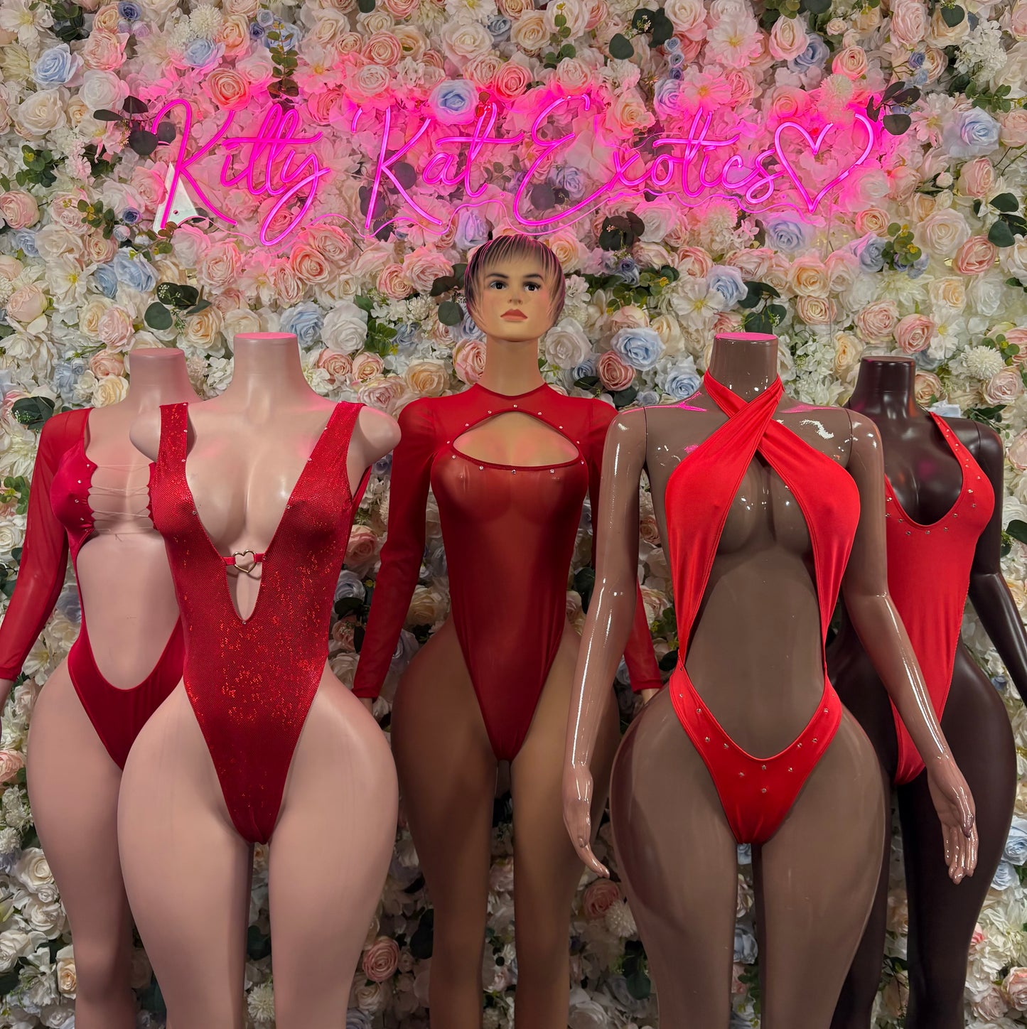 Set of red long-sleeve festival bodysuits on mannequins, deep front cutouts and back ties