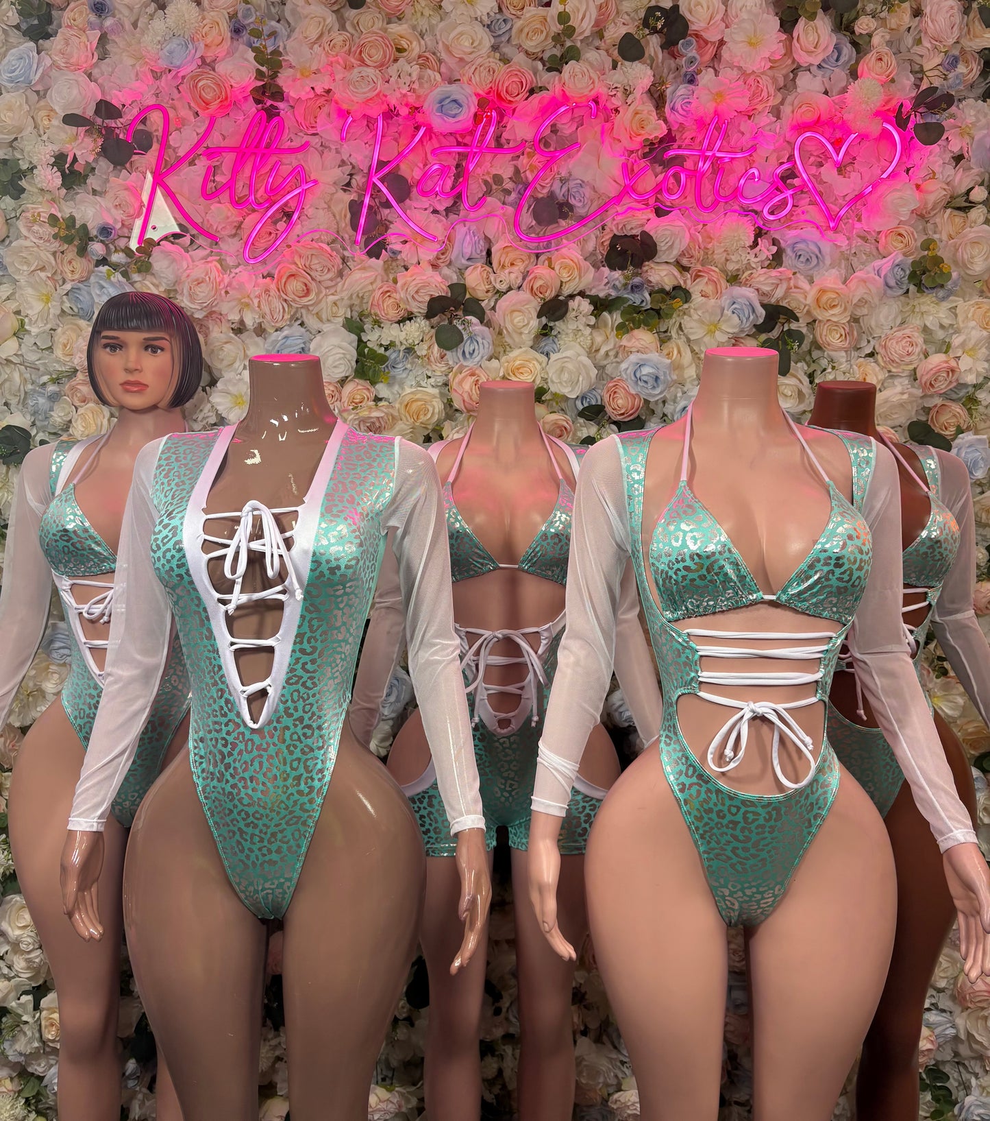 Aqua teal sequined bodysuits on mannequins with lace-up fronts and sheer sleeves