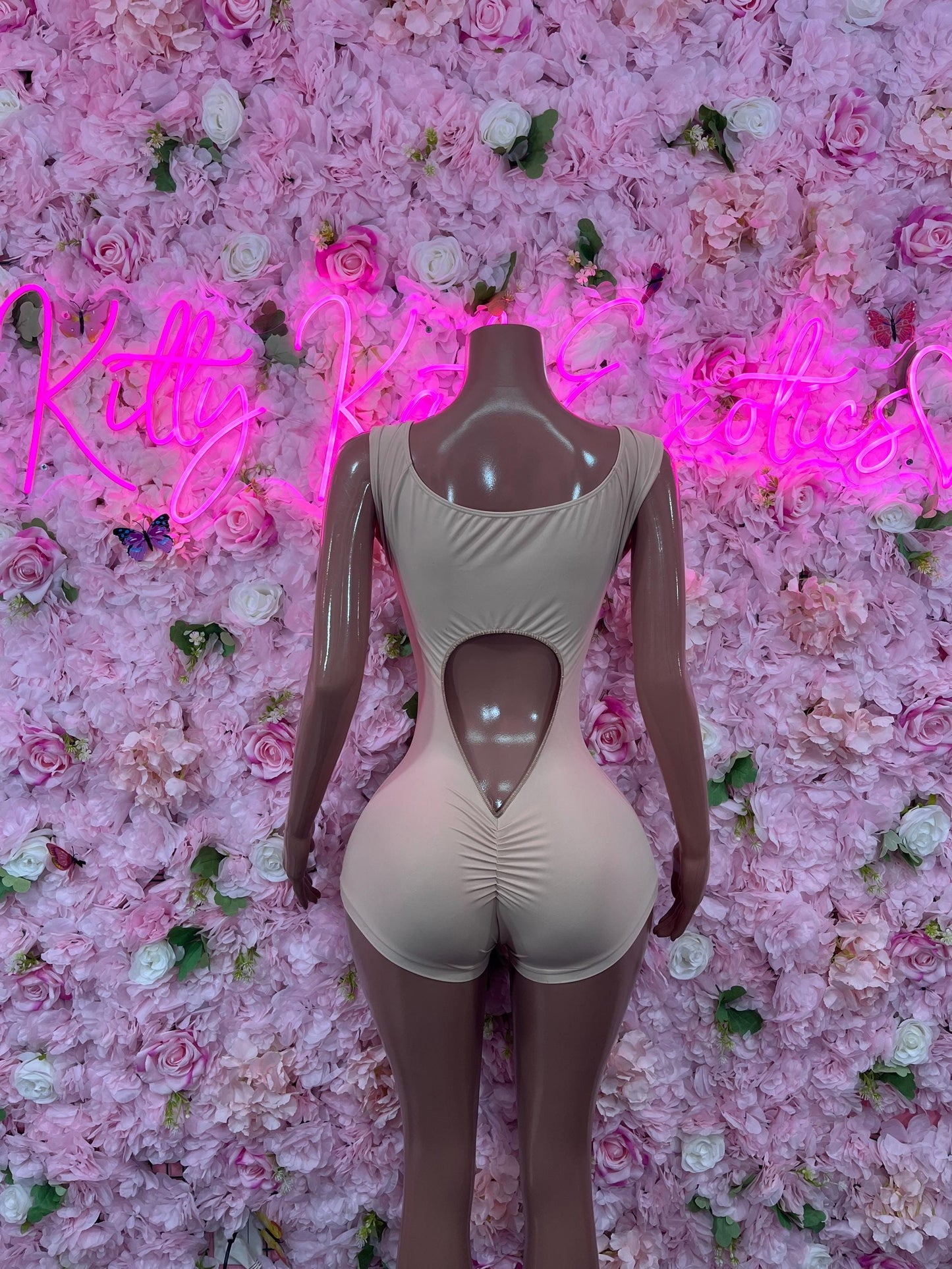 Nude one-piece bodysuit with long sleeves, square neckline, and thong-style bottom