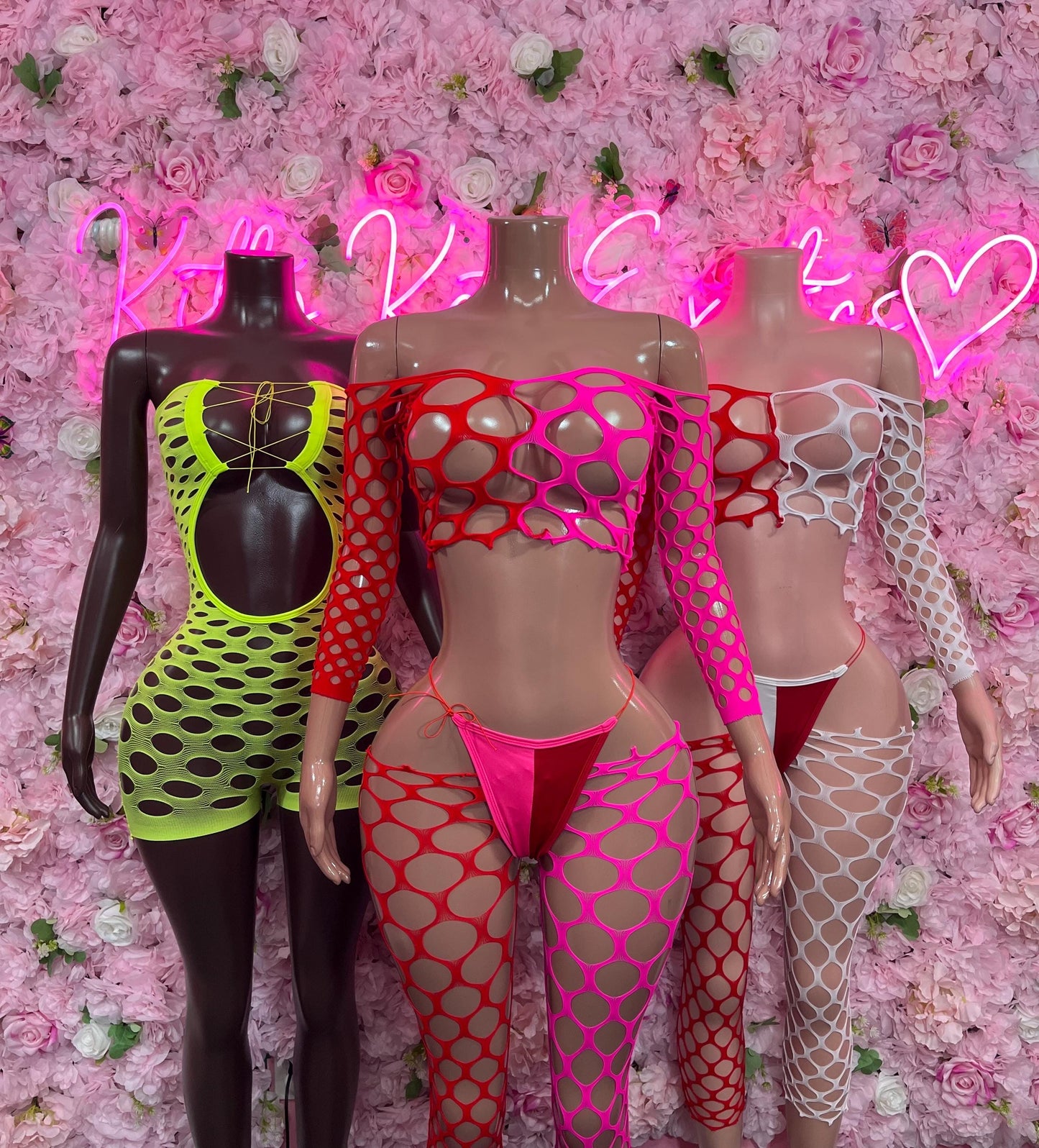 Neon fishnet two-piece dancewear bodysuits in green, red, and white on mannequins