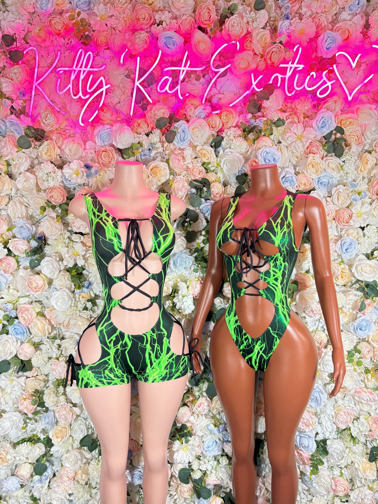 Two green one-piece bodysuits with crisscross black lace-up straps, side-by-side