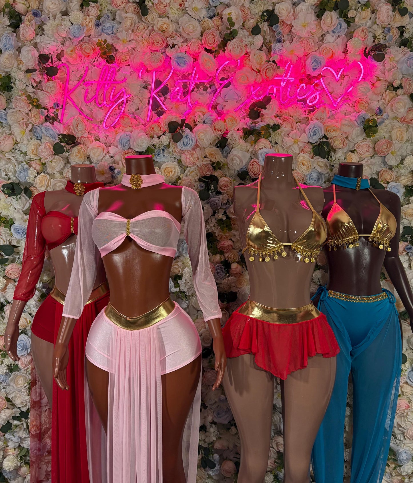 Adult cosplay costumes on mannequins: pink and red dress and blue pants with gold top