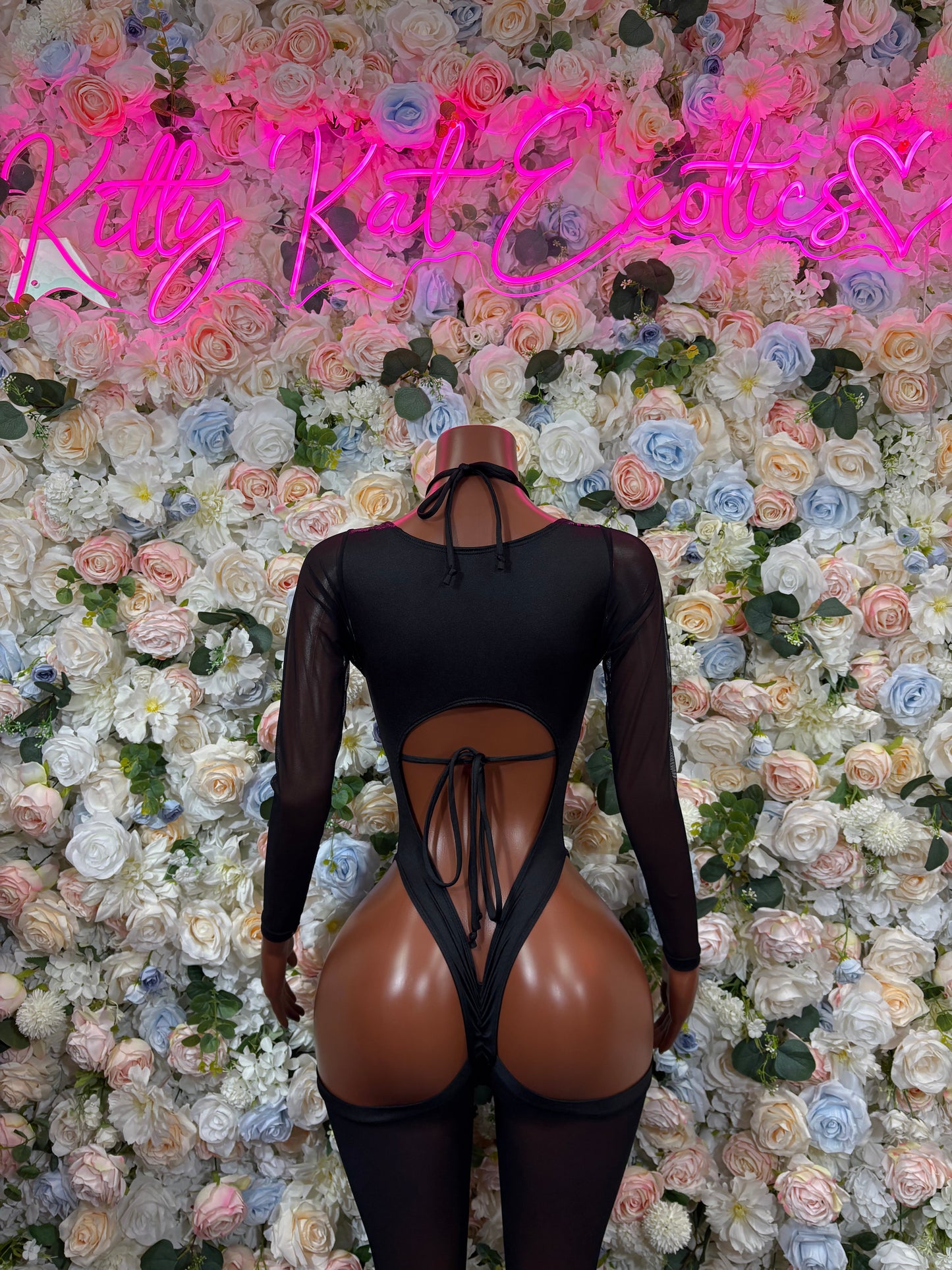 Back view: black long-sleeve bodysuit with purple dragon straps and open cutout