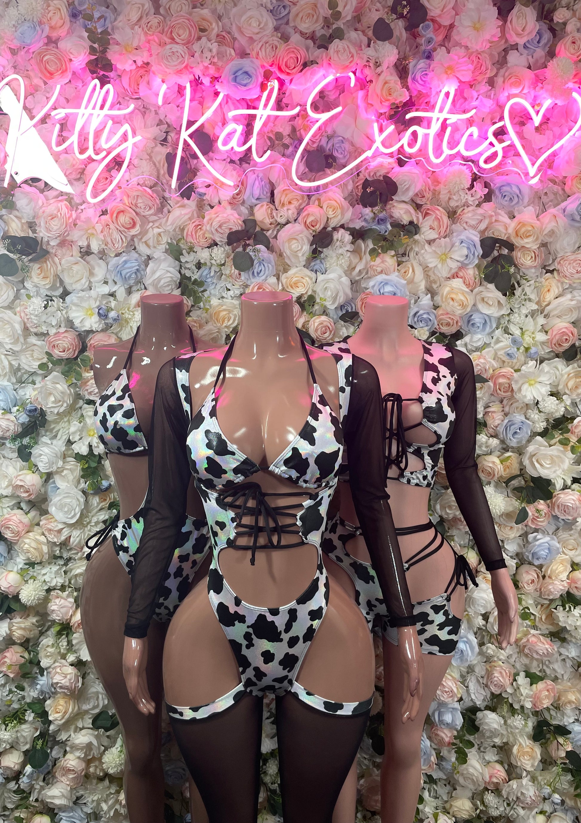 Cow print bodysuits with black mesh long sleeves and lace-up cutouts on mannequins