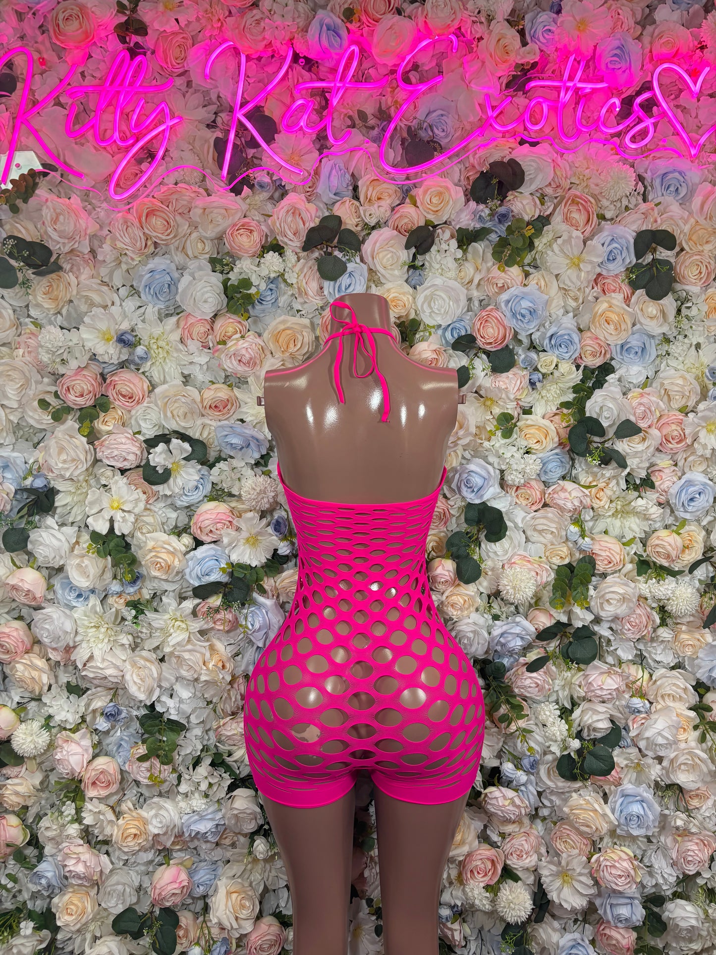 Hot pink fishnet halter romper with oval cutout, short bottoms, tie-neck style