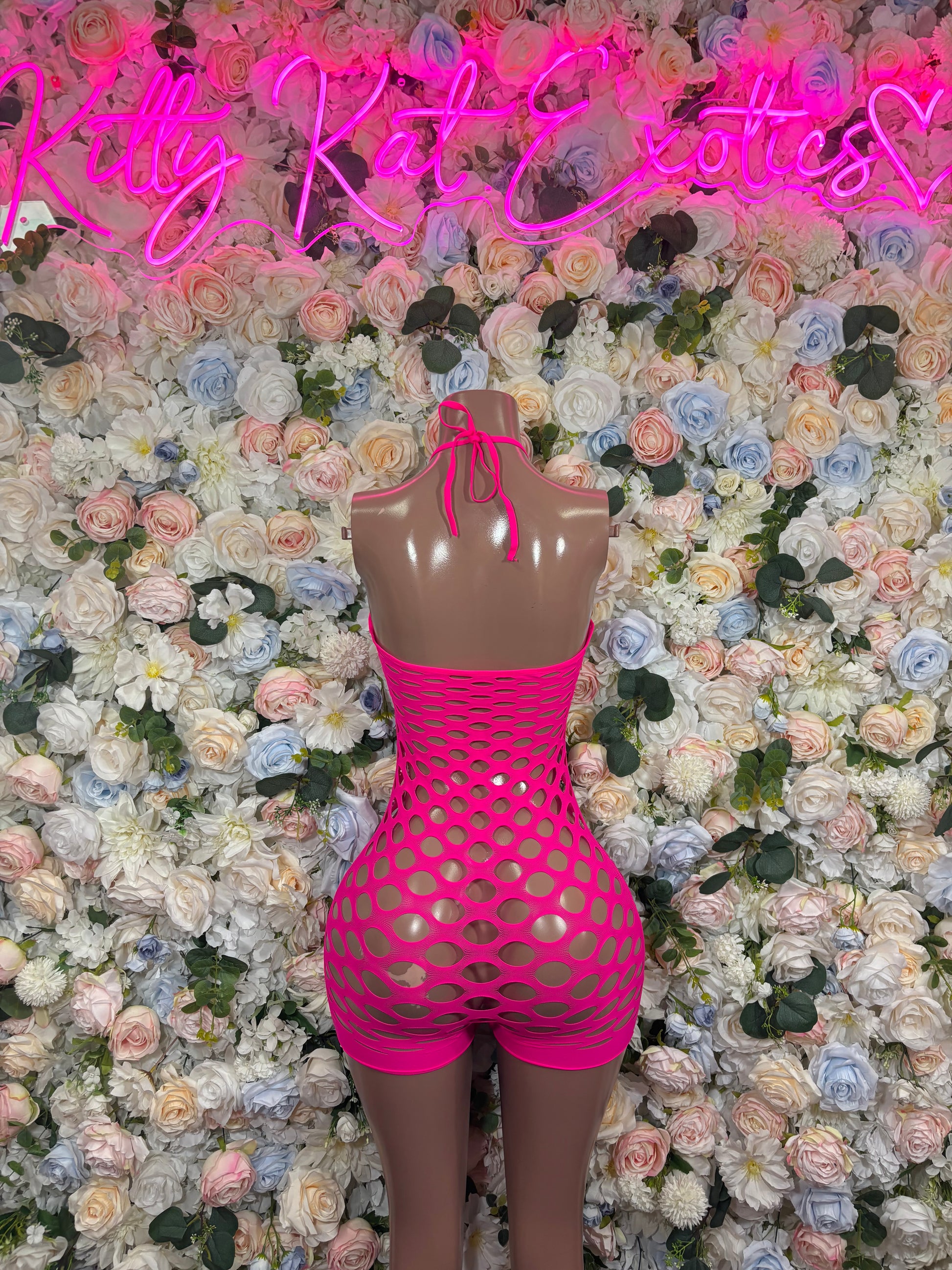 Hot pink fishnet halter romper with oval cutout, short bottoms, tie-neck style