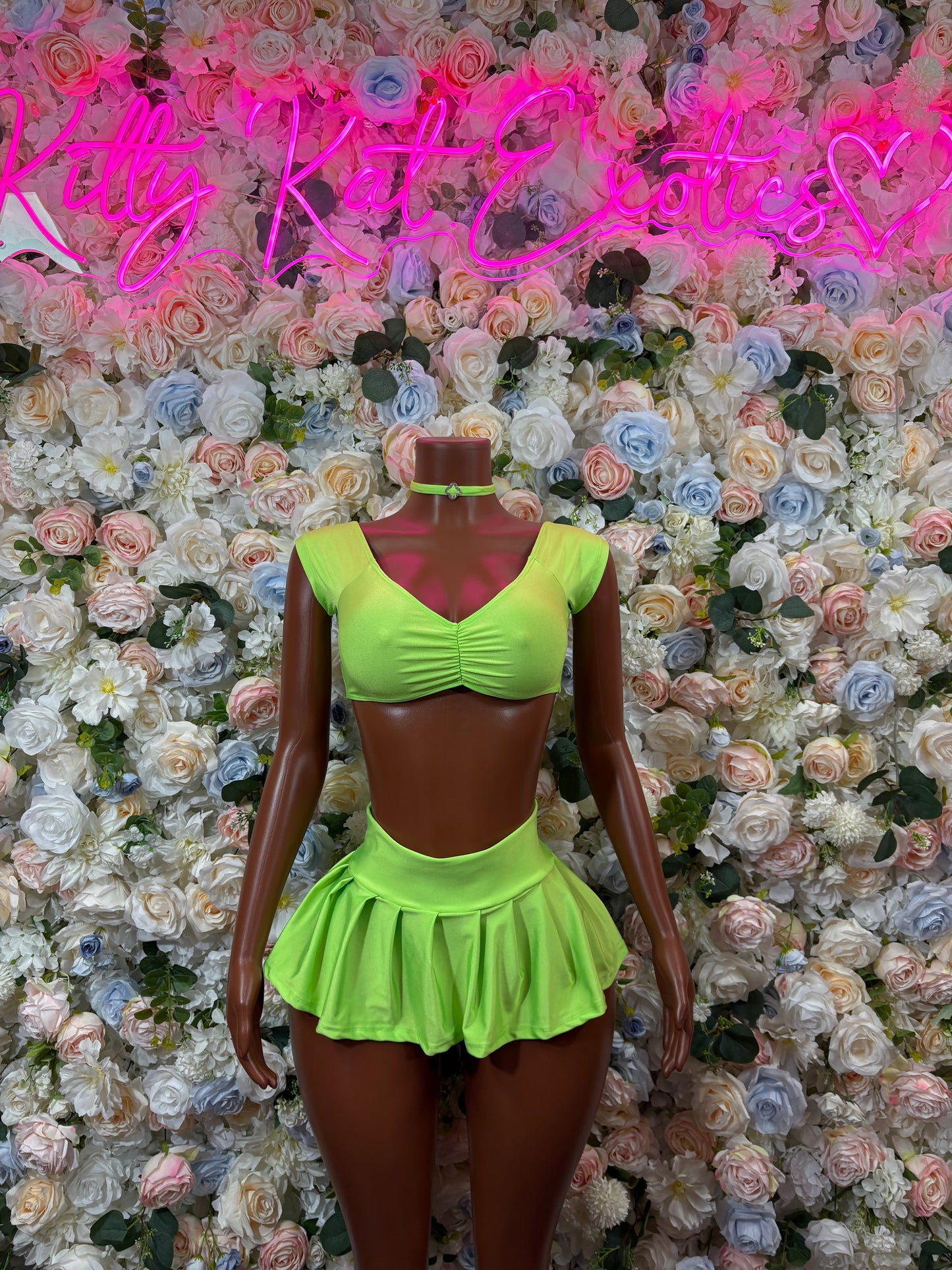 Green two-piece dancewear outfit with ruched crop top and flared mini skirt