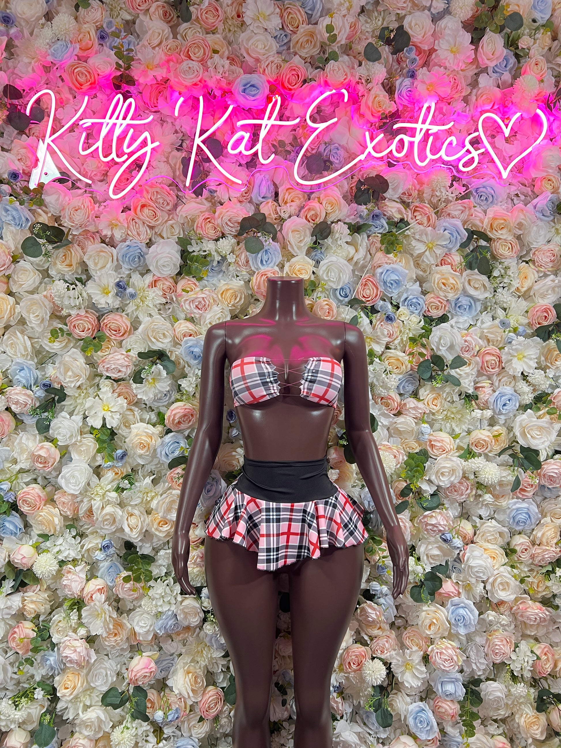 Pink plaid two-piece skirt set with plaid top and black waist belt on mannequin