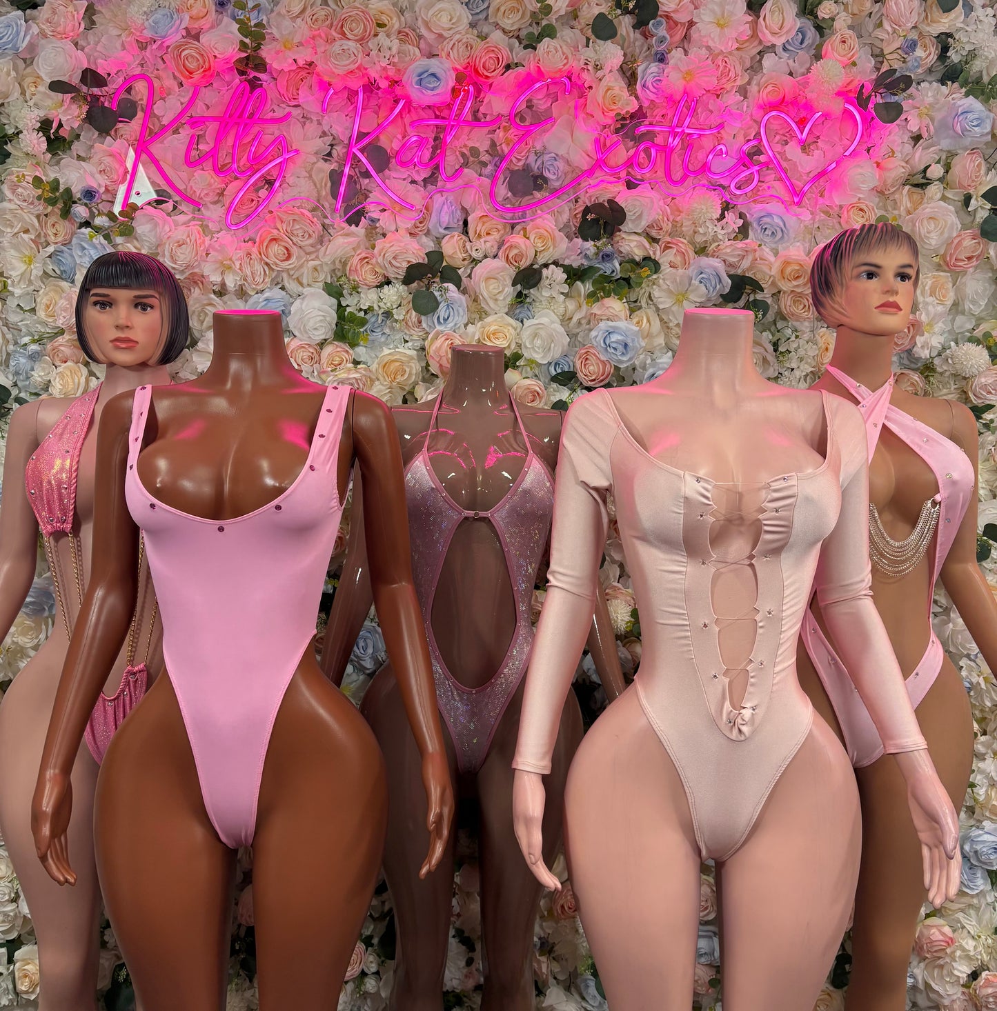 Pink one-piece bodysuit with halter neck, decorative straps, and chain trim