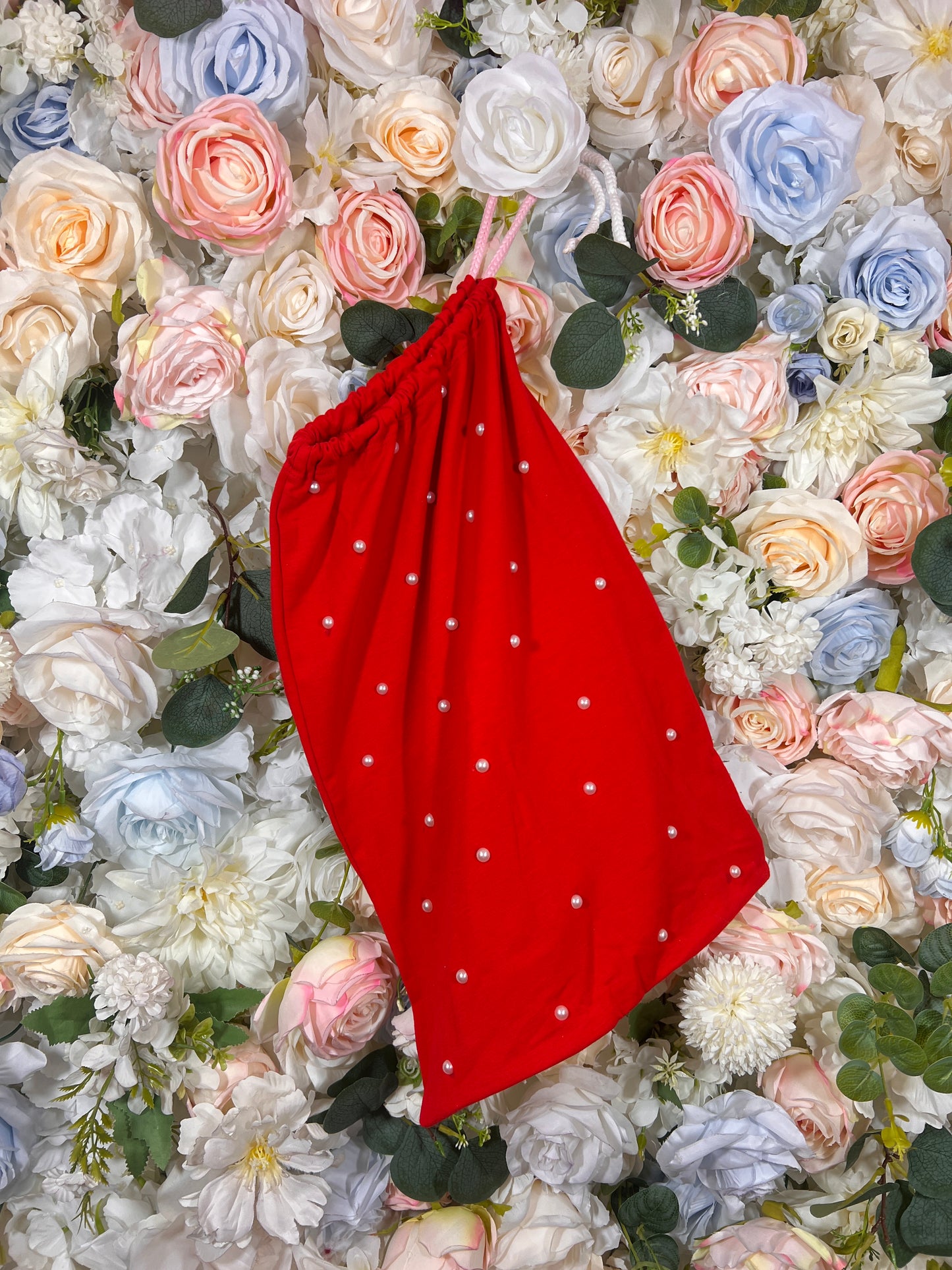 Red fabric money-pouch with gathered top, thin strap, and small white dot pattern