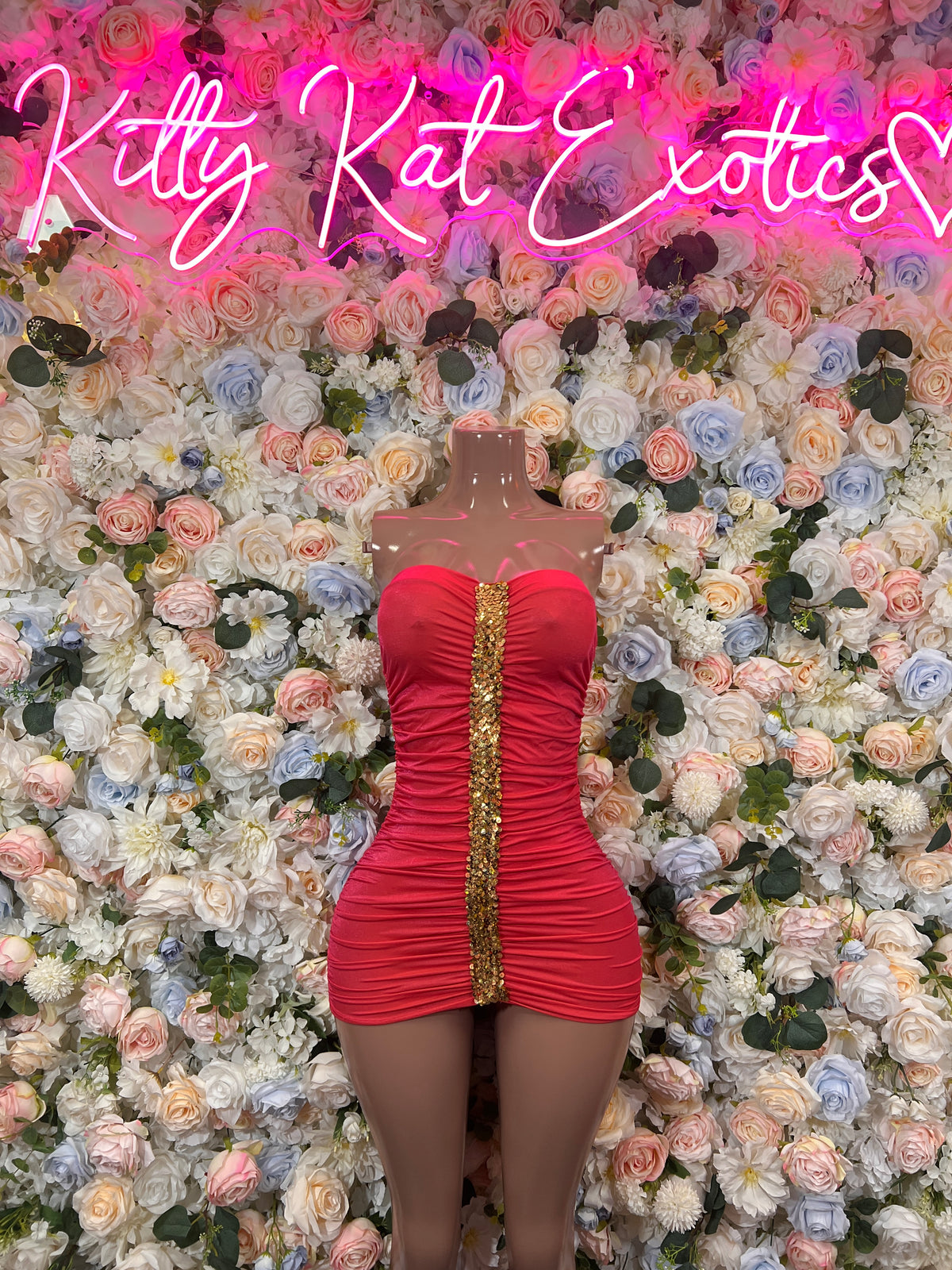 Coral red ruched strapless mini dress with vertical gold chain detail, mannequin