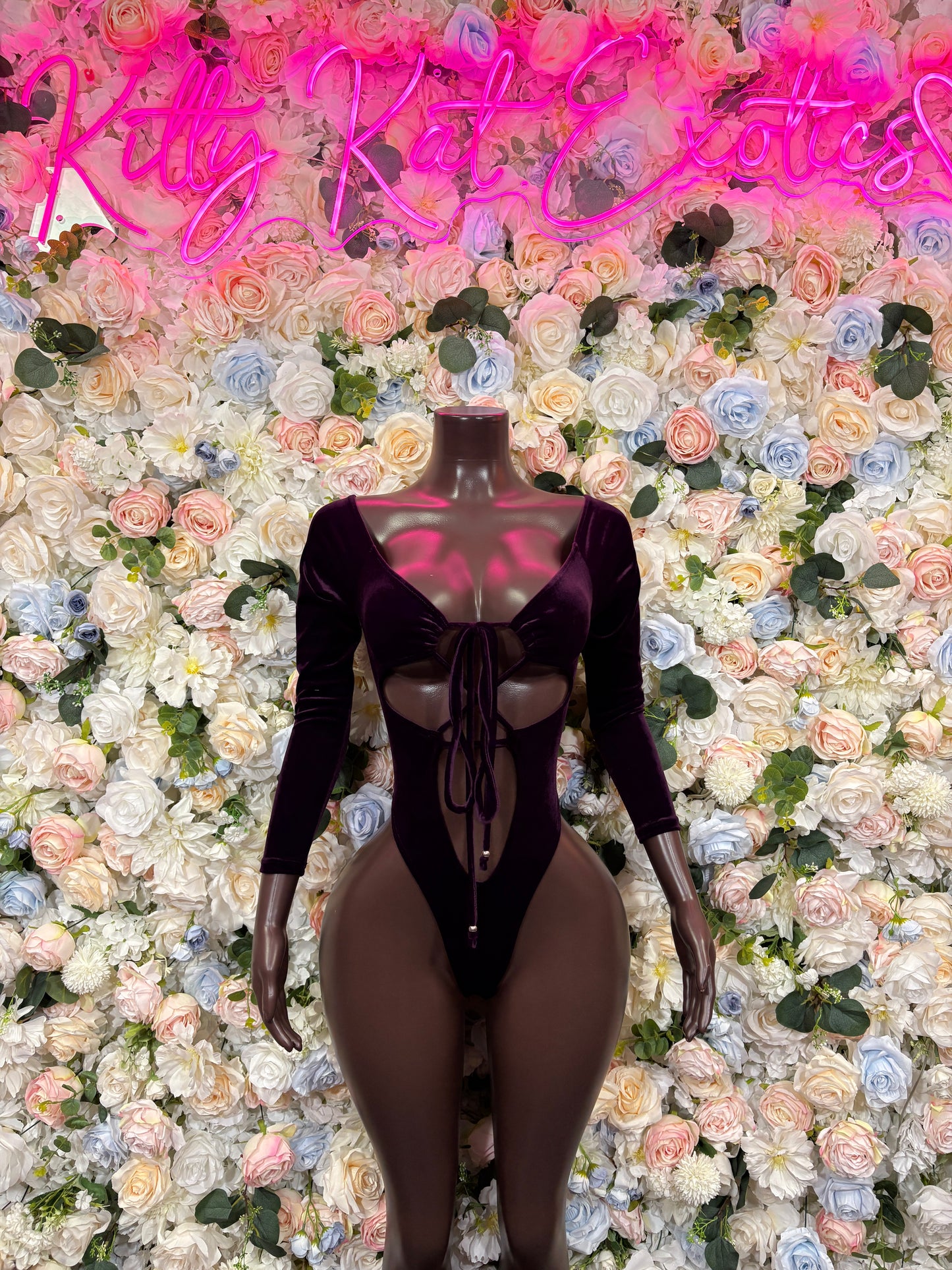 Purple velvet one-piece bodysuit with long sleeves, lace-up neckline, and front cutouts