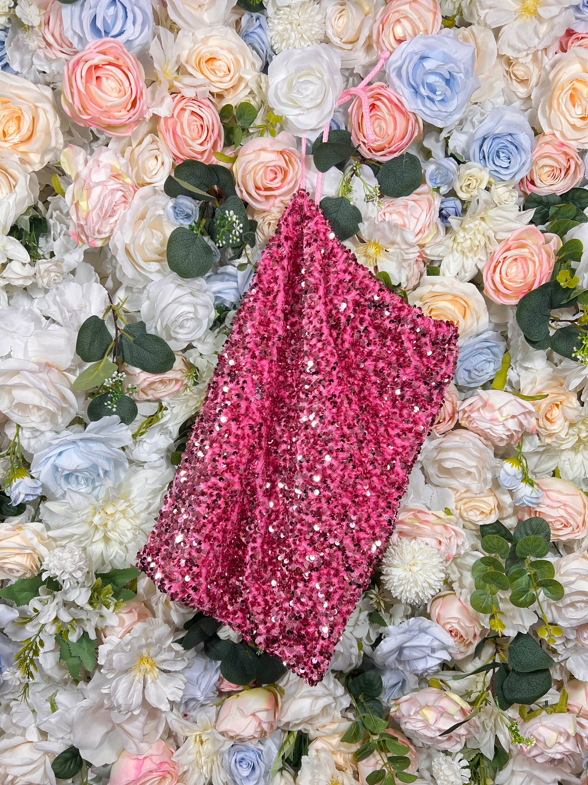 Pink velvet money bag covered in sparkling sequins, angled view