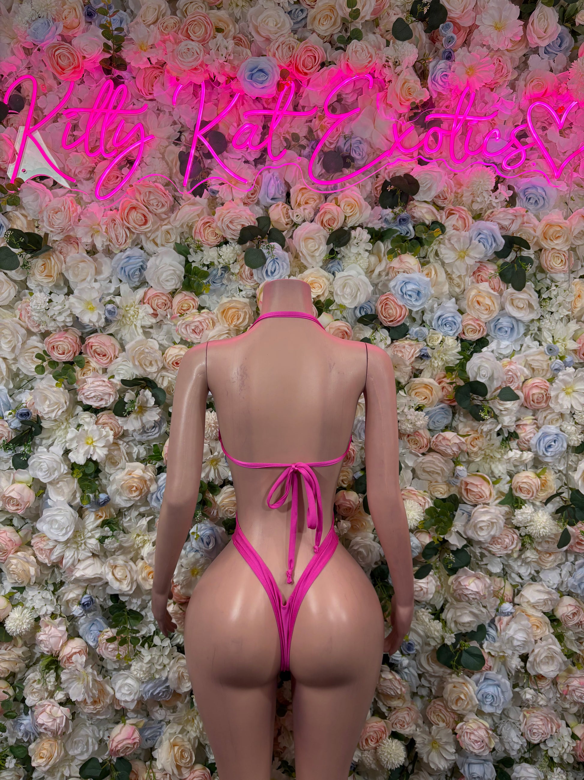 Pink bodysuit with open back, crisscross straps, and tie at neck