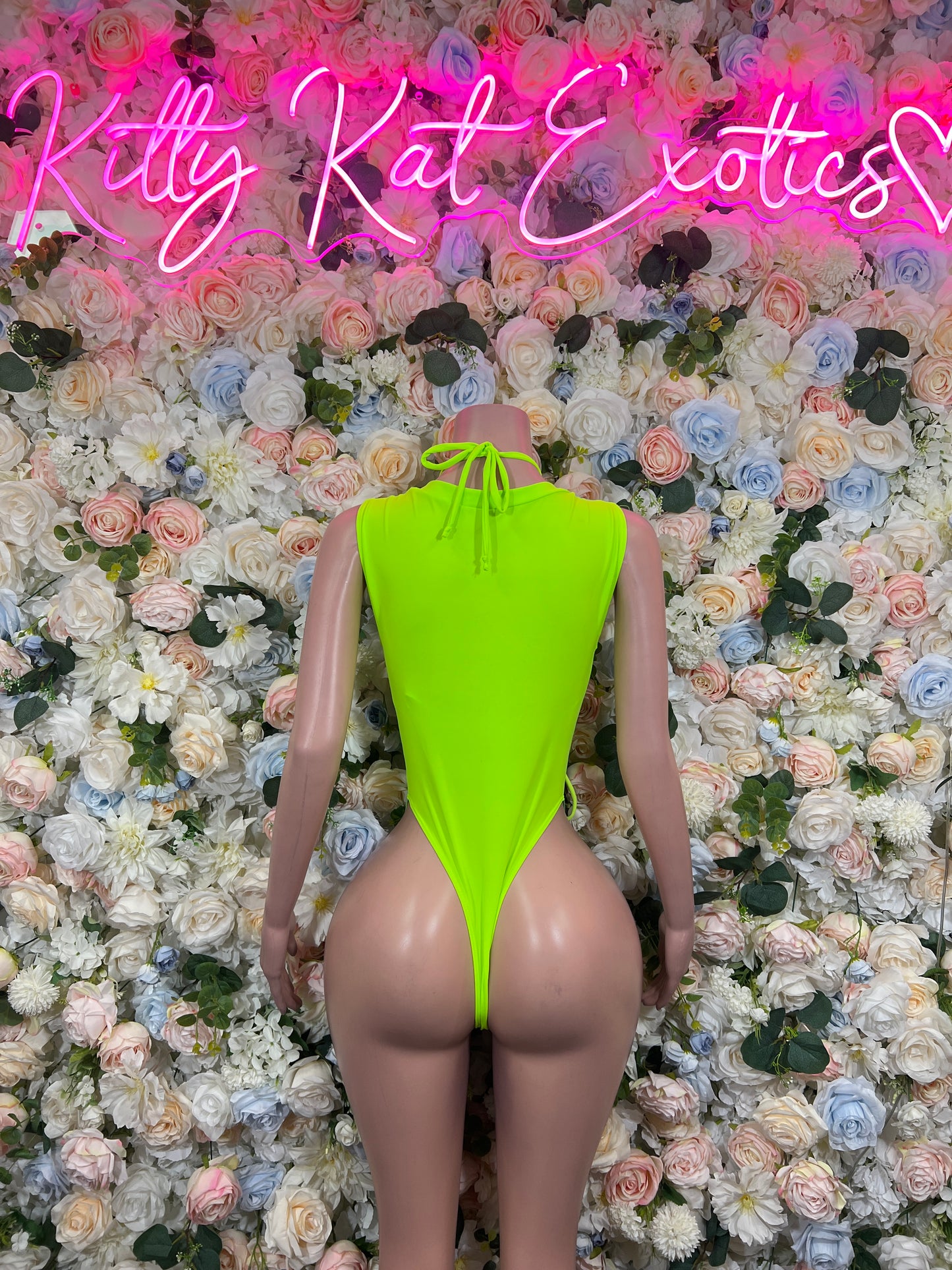 Holographic neon green bodysuit with lace-up front, high-cut thong bottom on mannequin