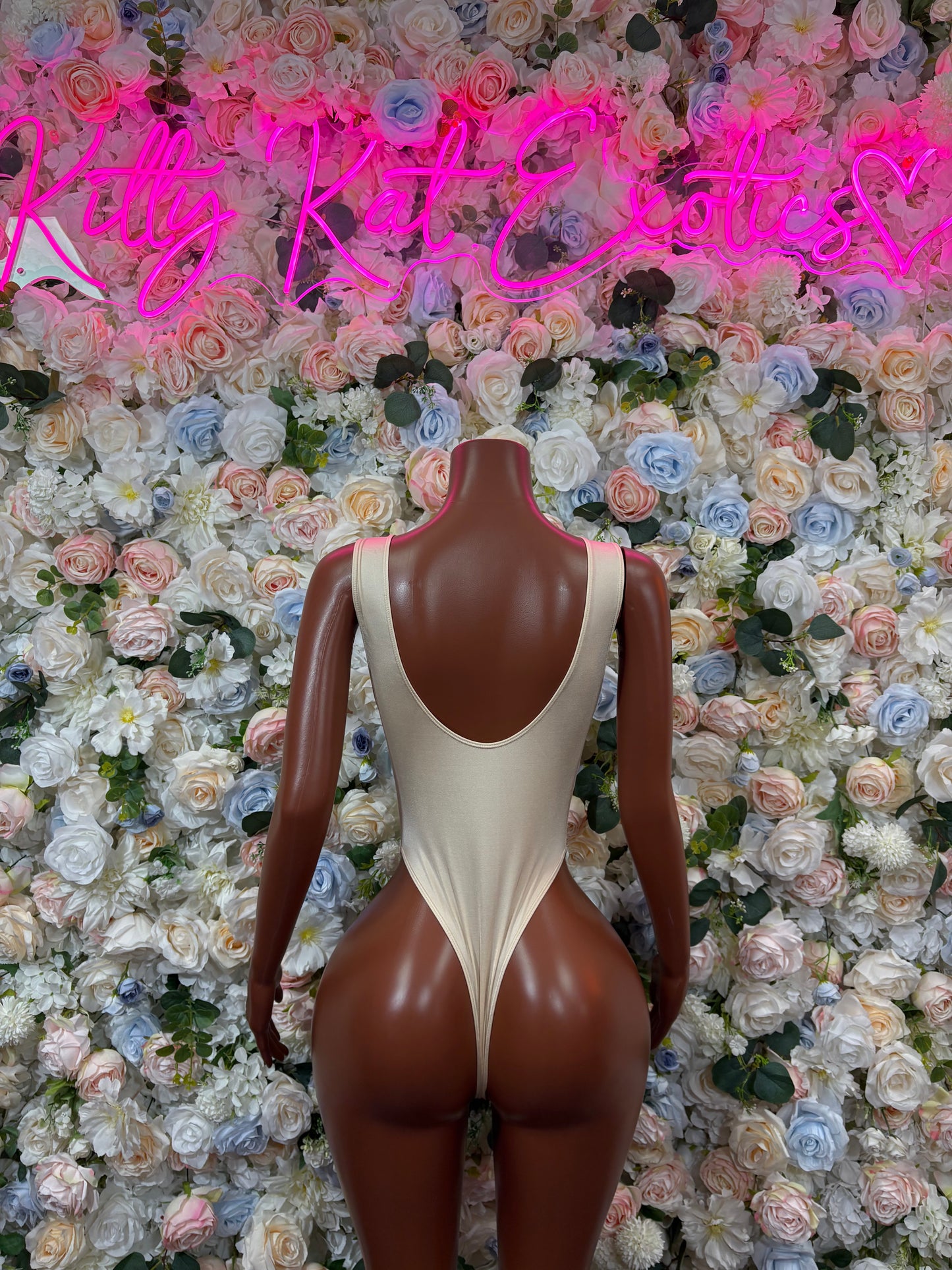 Cream one-piece nude bodysuit with scoop neckline and central open-back cutout