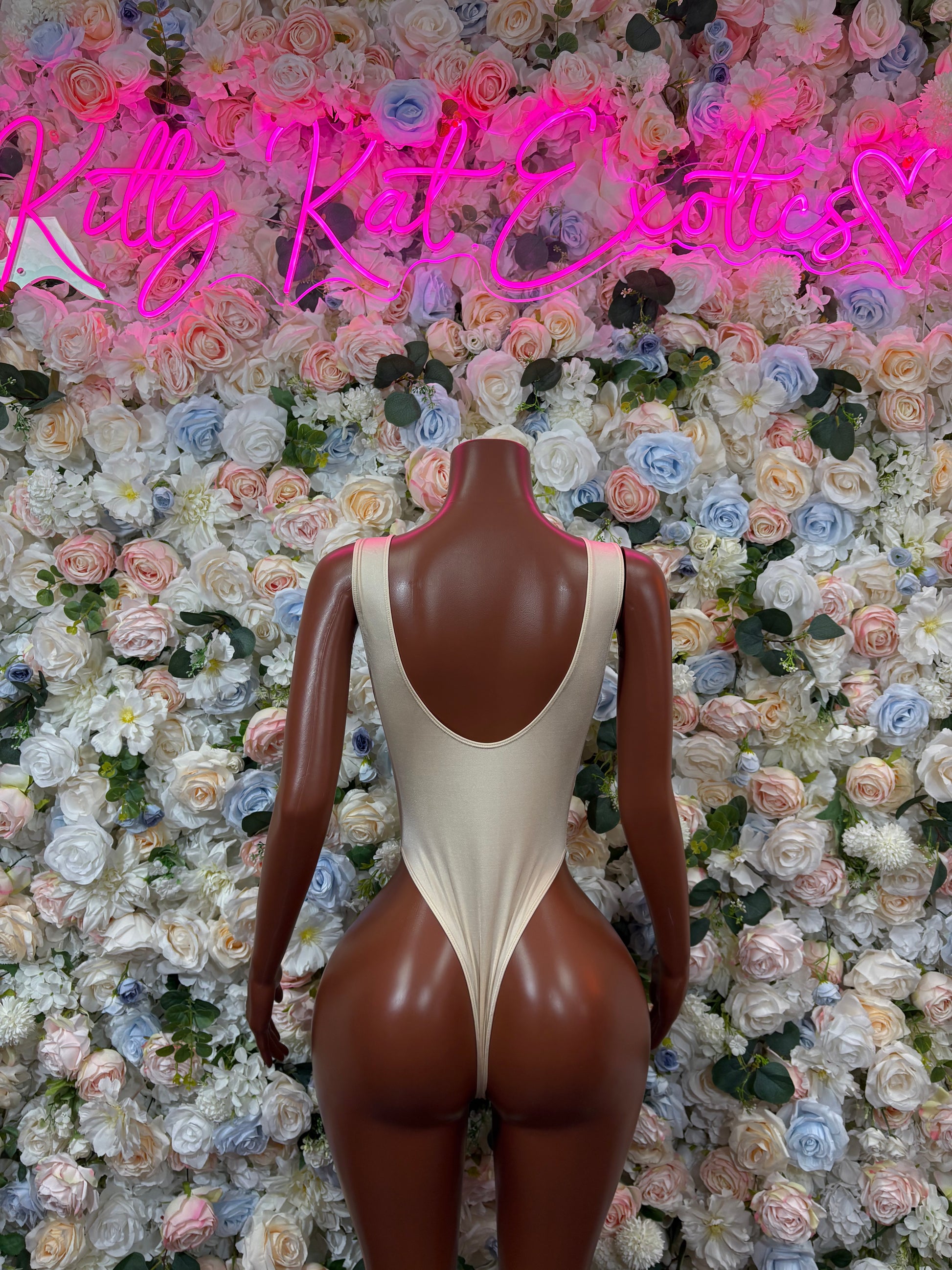 Cream one-piece nude bodysuit with scoop neckline and central open-back cutout