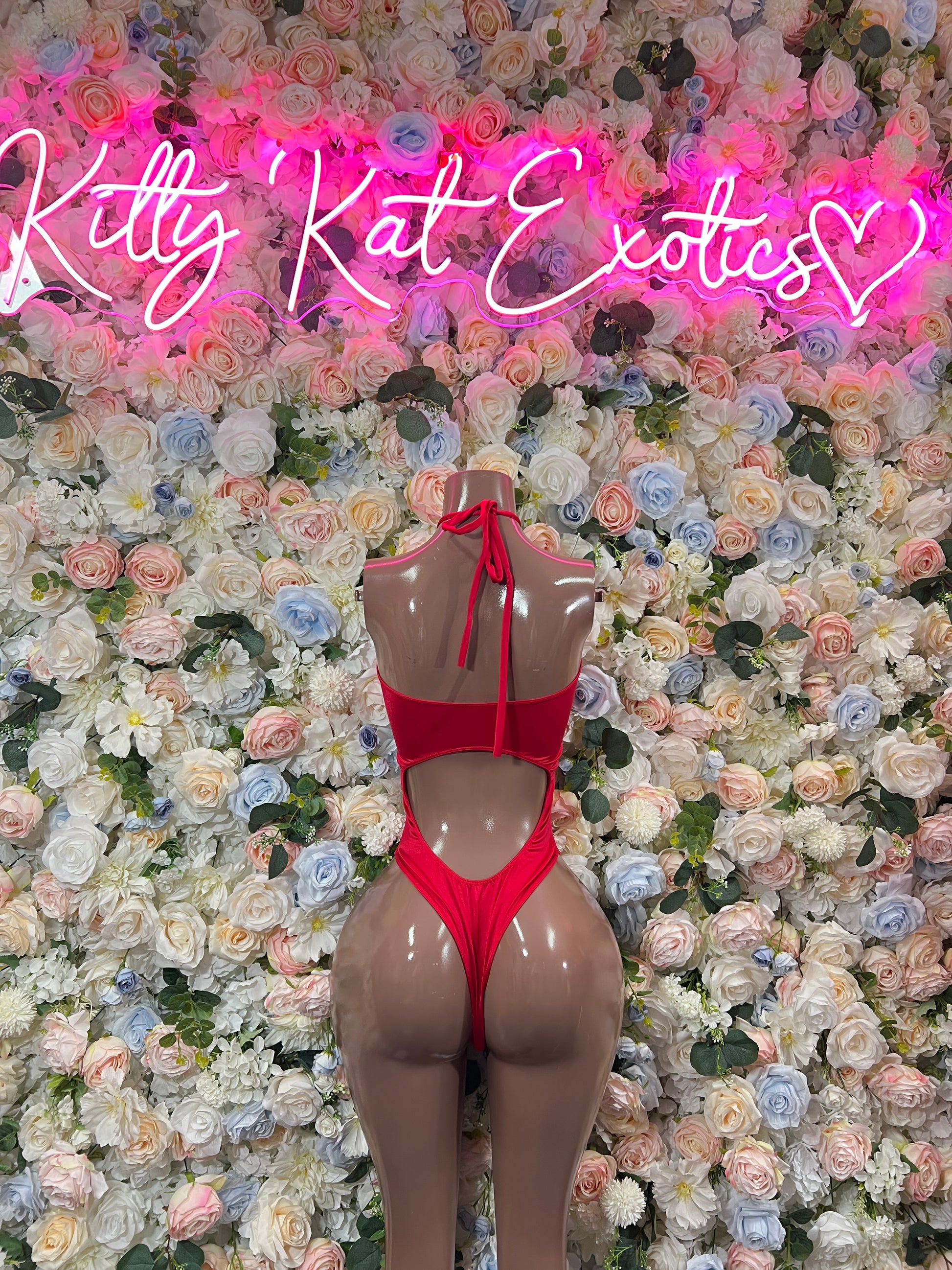 Red one-piece bodysuit with halter straps, back bow tie, and open sides