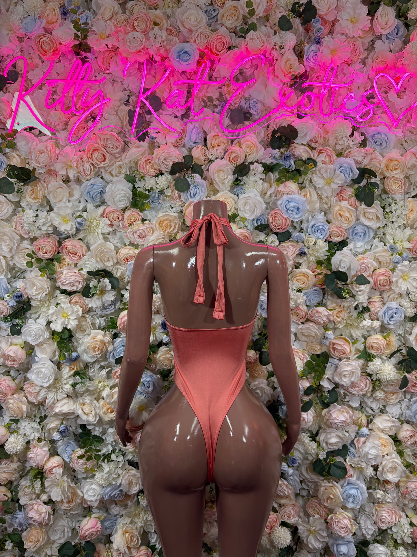 Rose-pink high-cut bodysuit, open back with tied halter and vertical lace-up.