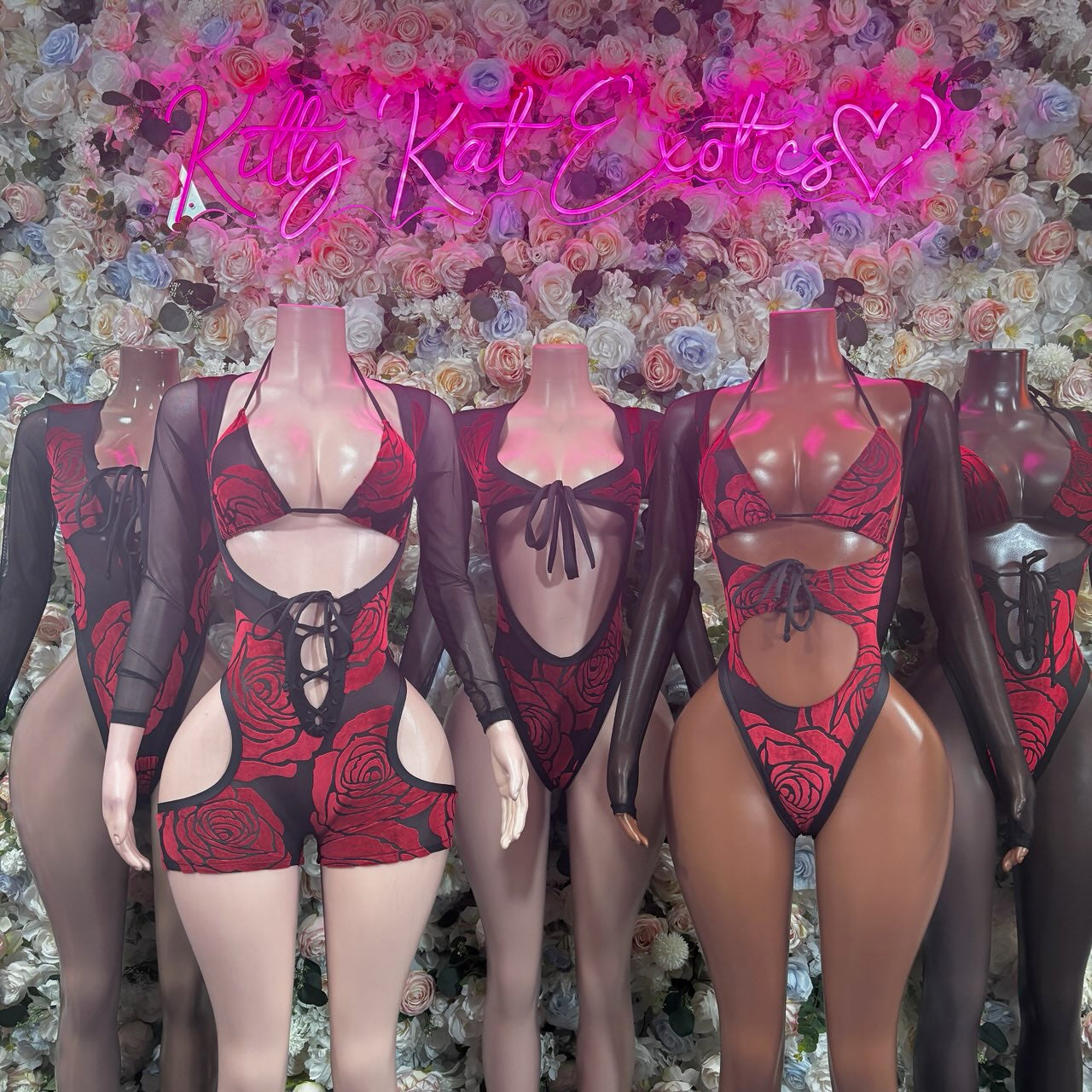 Multiple black sheer bodysuits with red rose print and long sleeves on display