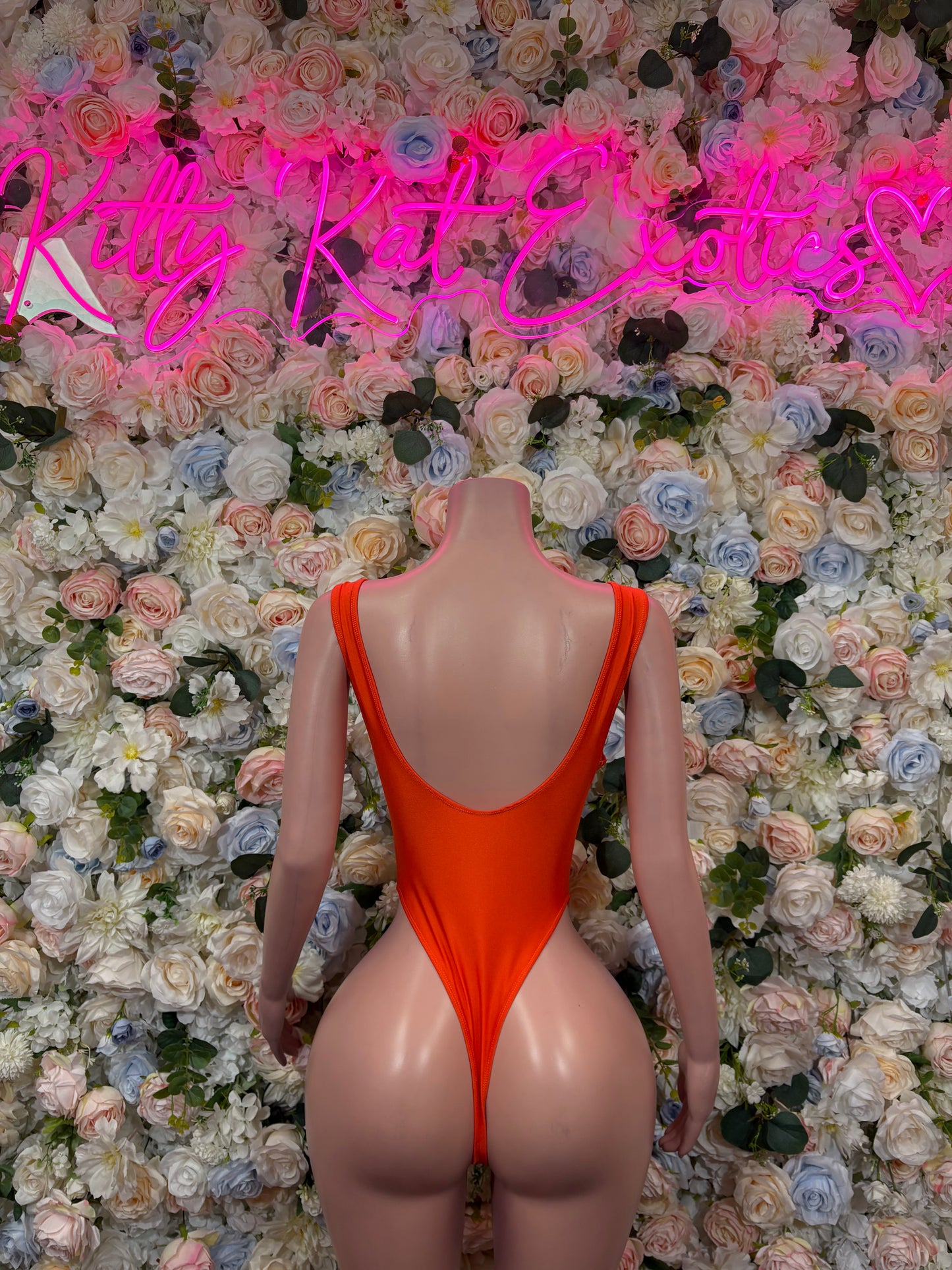 Orange one-piece bodysuit with crossed-back straps and low back cutout