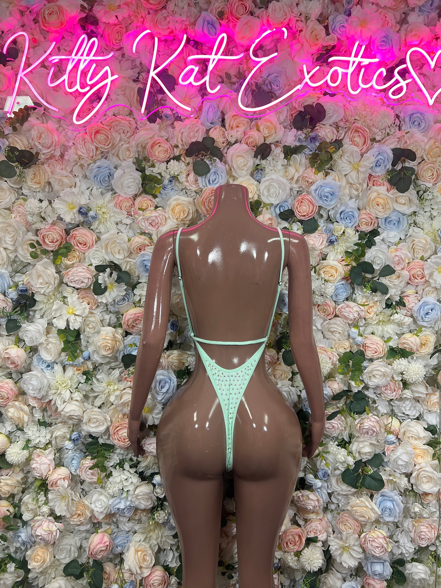 Teal rhinestone bodysuit with open back and thin straps on mannequin