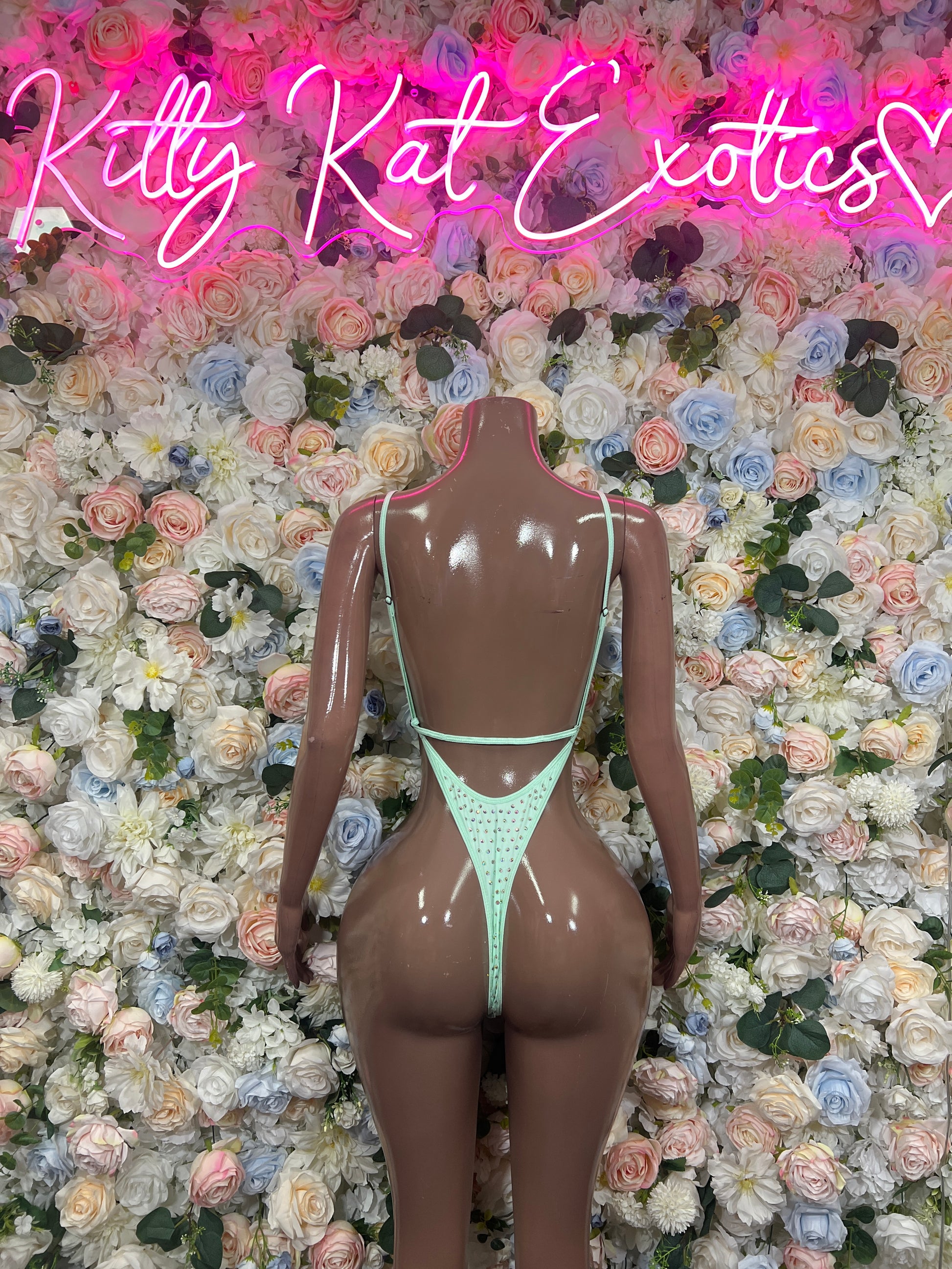 Teal rhinestone bodysuit with open back and thin straps on mannequin