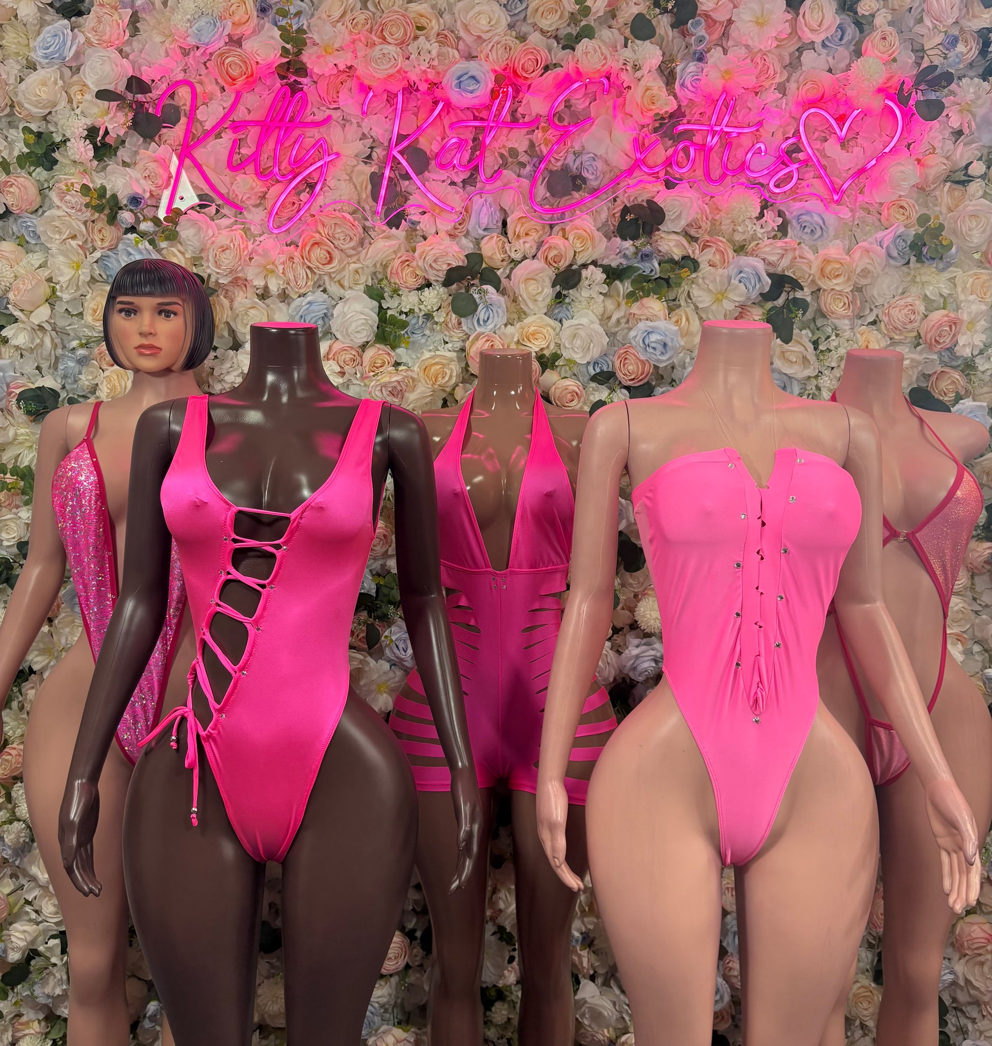 Pink ravewear one-piece bodysuits on mannequins, assorted styles with cutouts