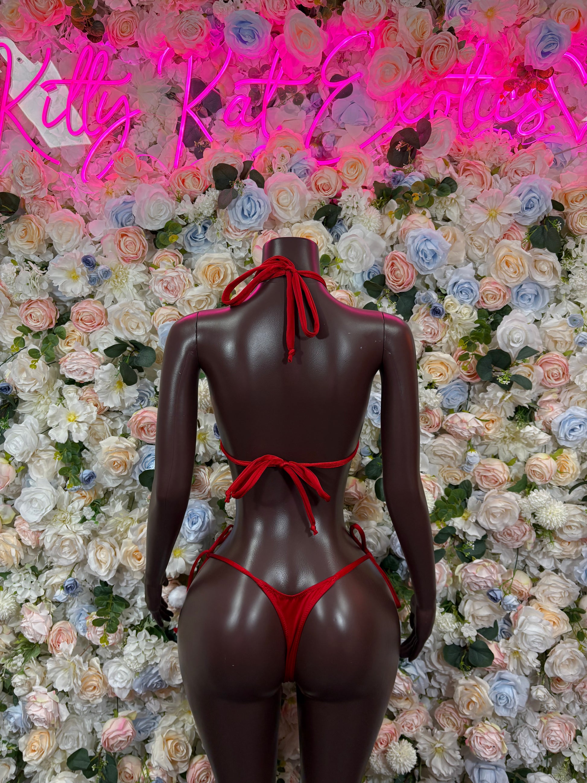 Back view of red velvet two-piece bodysuit on mannequin, halter ties and thong