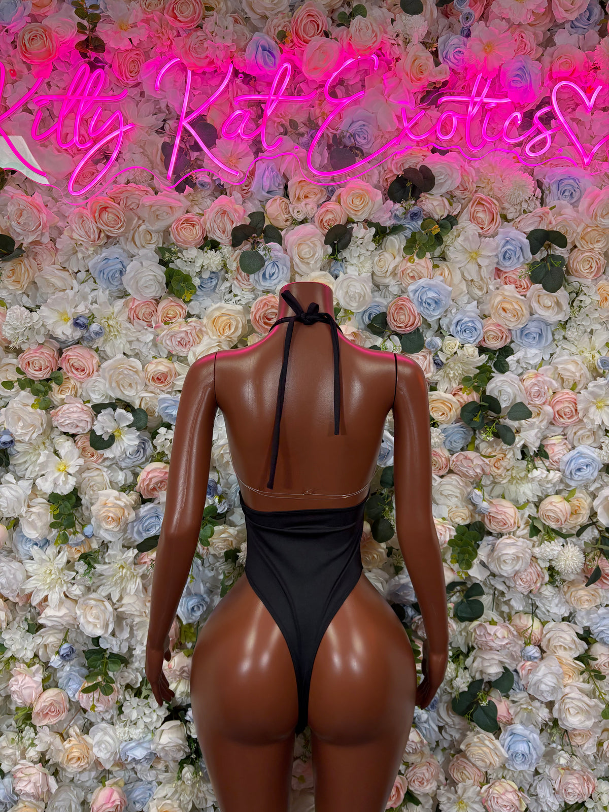 Black one-piece slingshot bodysuit with open back and thong-cut leg