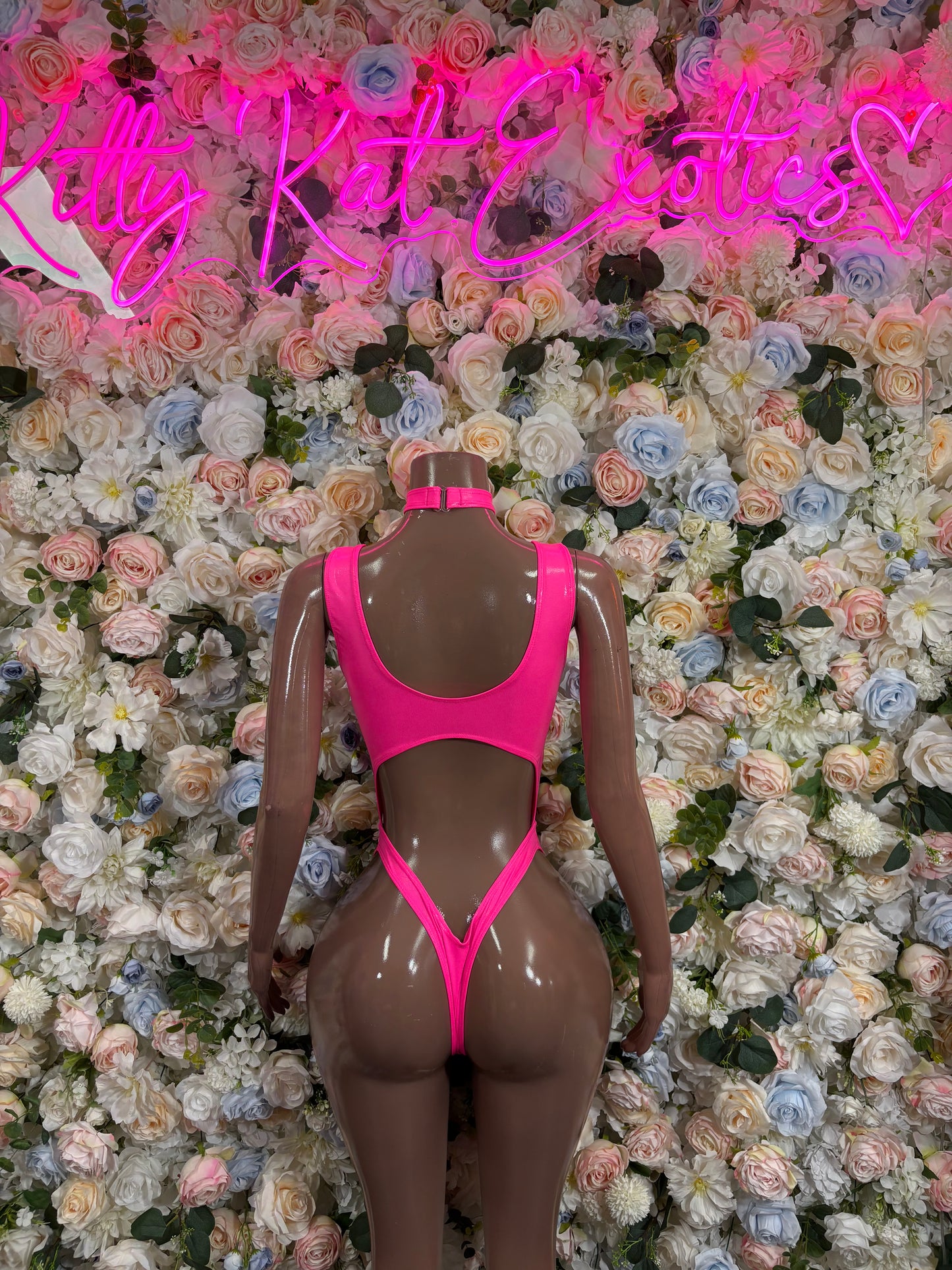Pink one-piece bodysuit on mannequin, open back with halter strap and high-cut leg