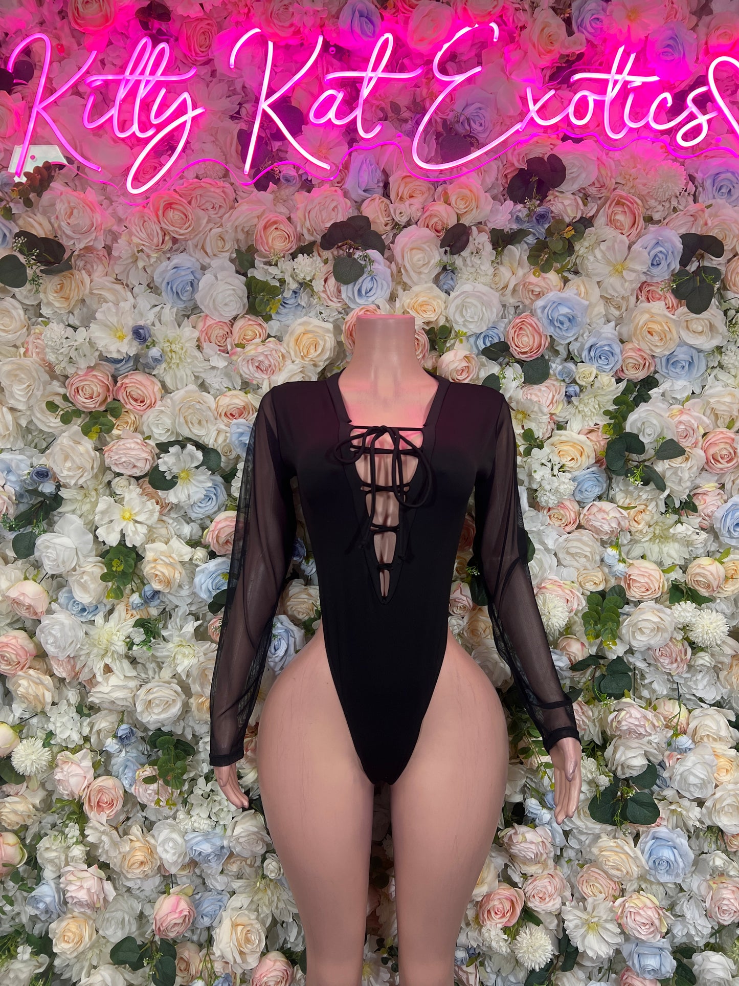 Black backless bodysuit with lace-up crisscross panel, sheer sleeves, high-cut leg