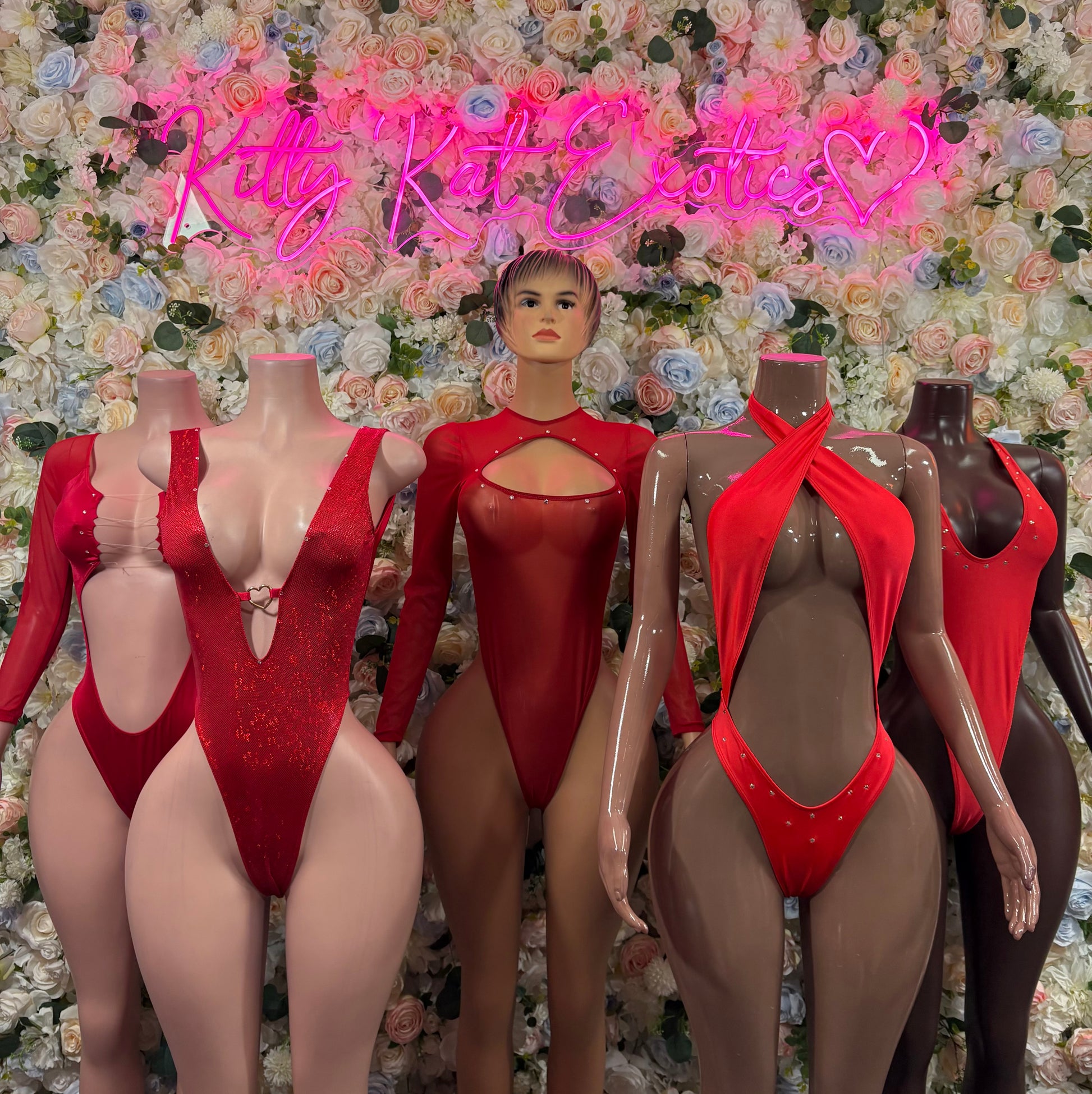 Set of red long-sleeve festival bodysuits on mannequins, deep front cutouts and back ties