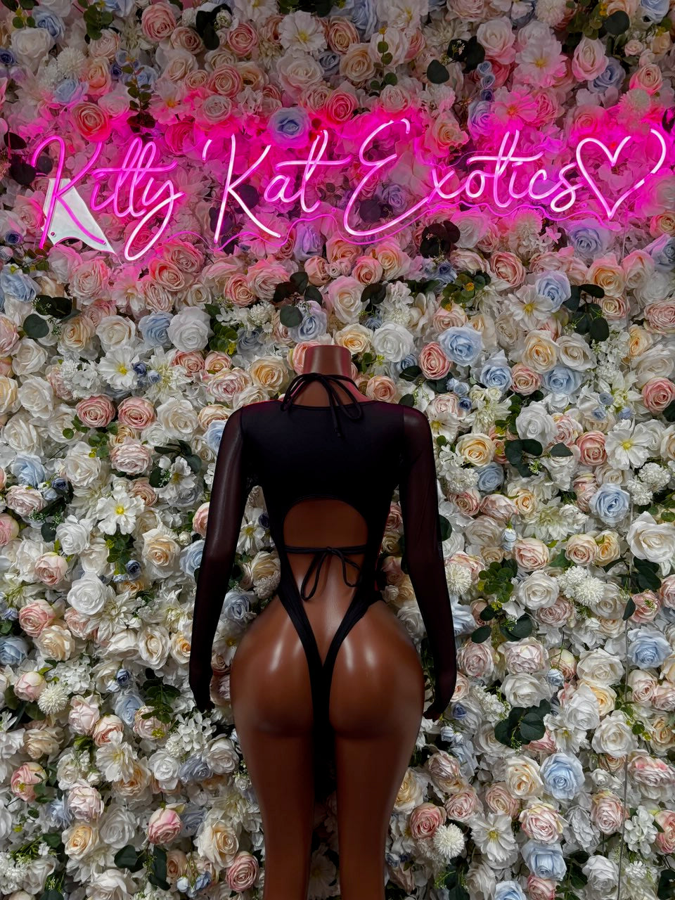 Rose-print sheer bodysuit with open back and tied straps on mannequin