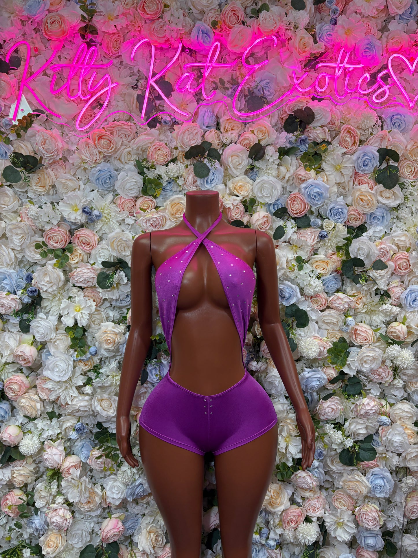 Purple one-piece rave bodysuit with halter neck, open back cutout, and thong bottom