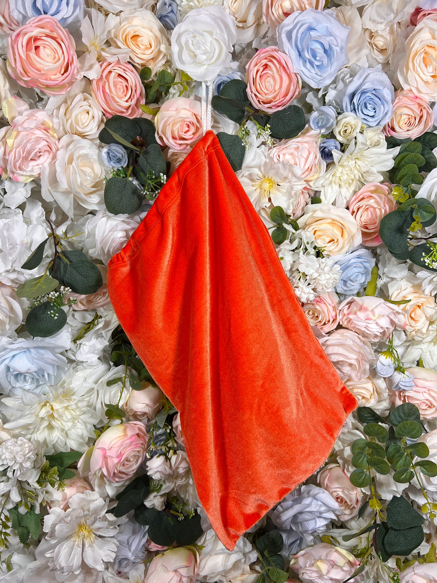Orange velvet money pouch with gathered top, glossy finish, no visible strap