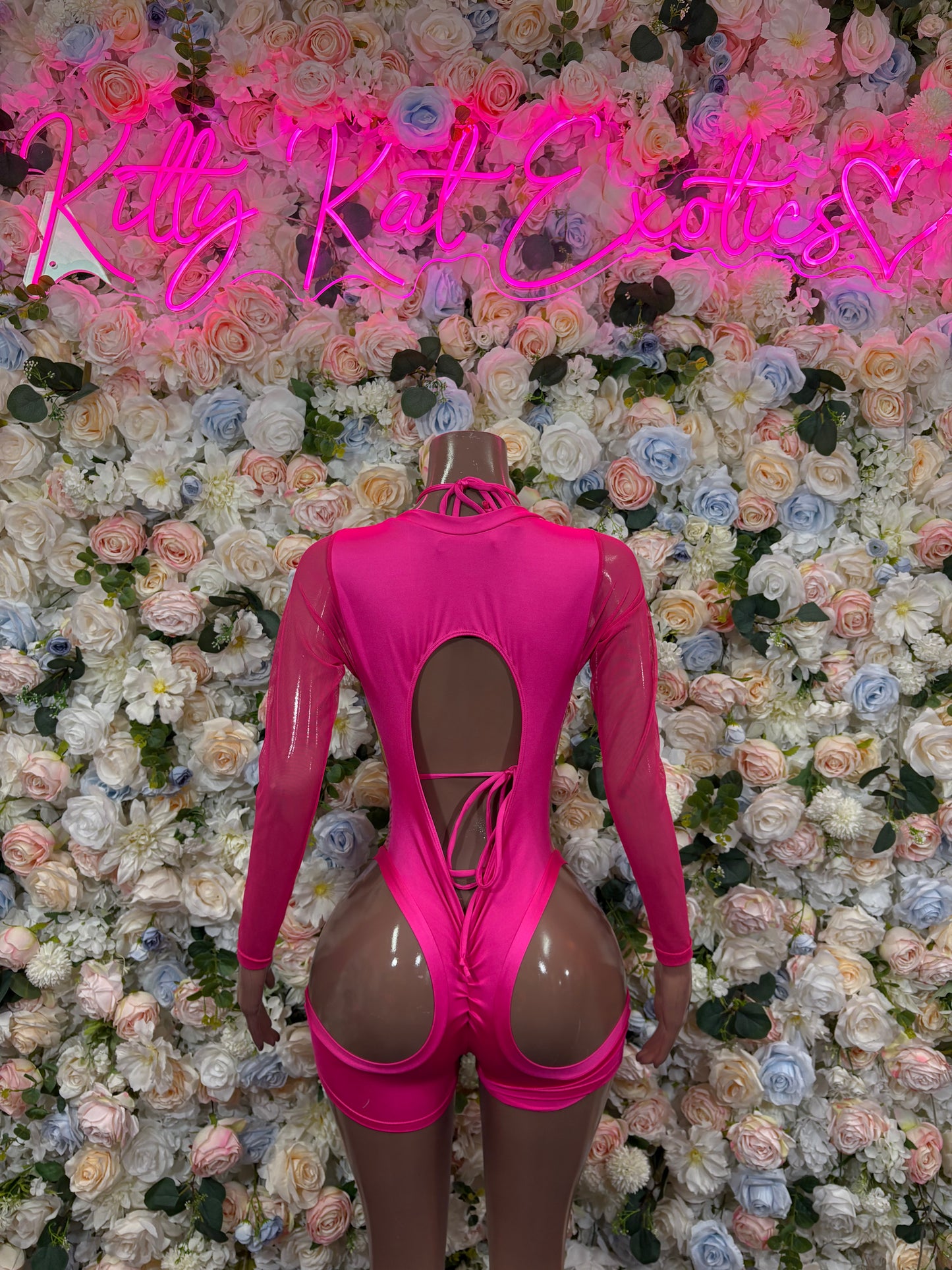 Pink metallic hologram bodysuit with long sleeves, open back cutout and strappy design