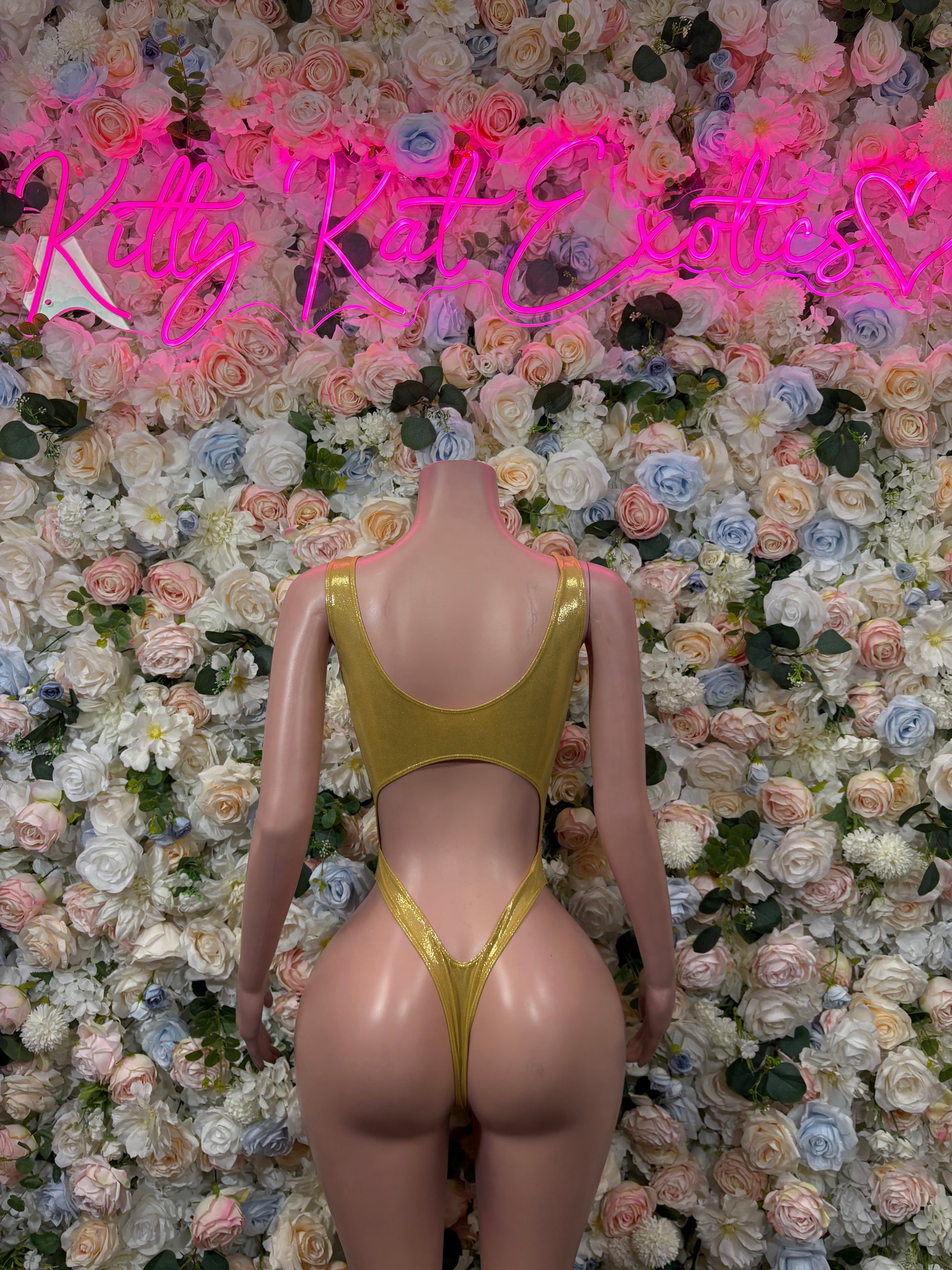 Gold one-piece bodysuit with thin straps, scoop neckline, and high-cut leg openings