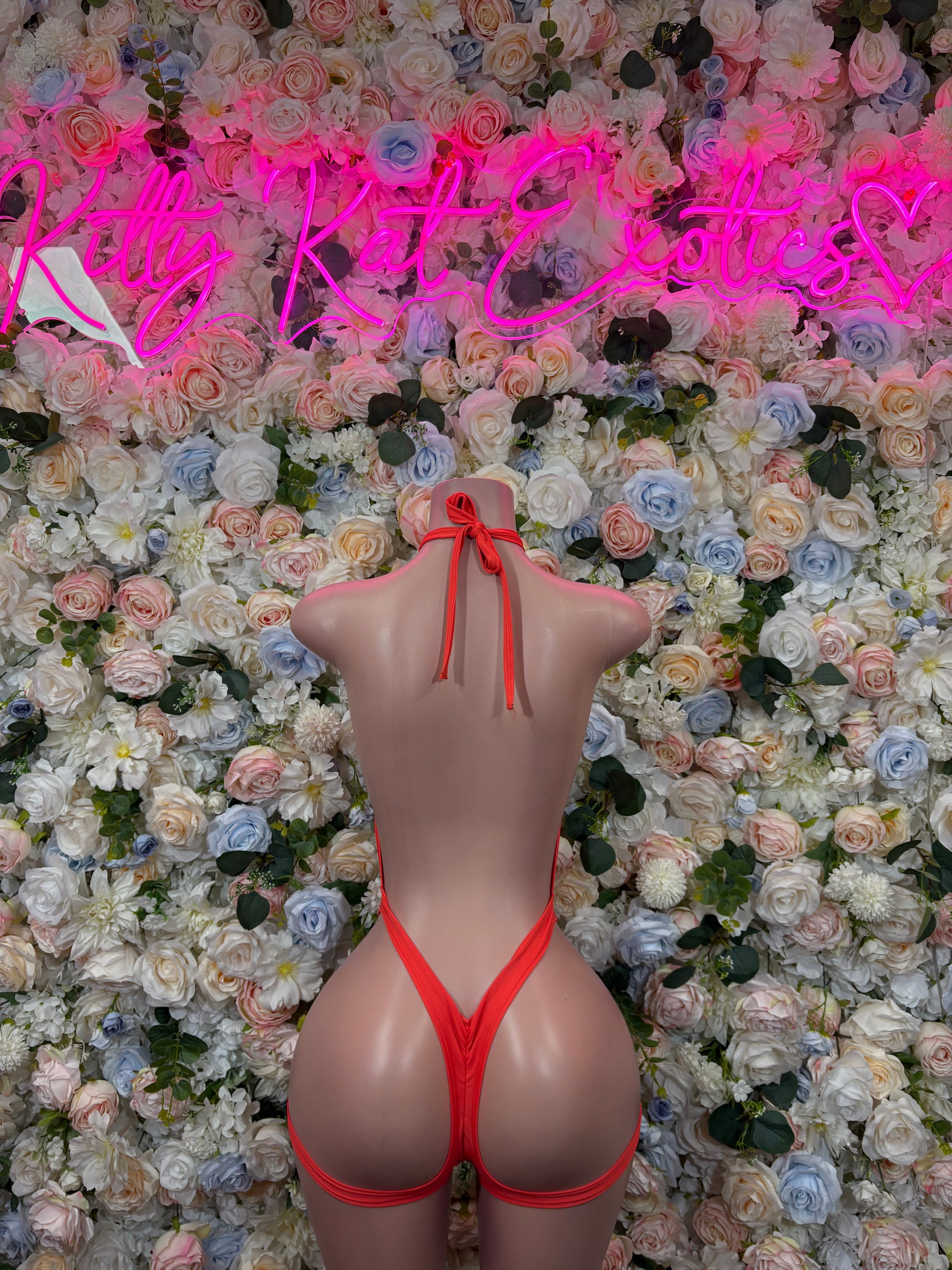 Orange halter bodysuit with crisscross open-back straps and minimal thong coverage
