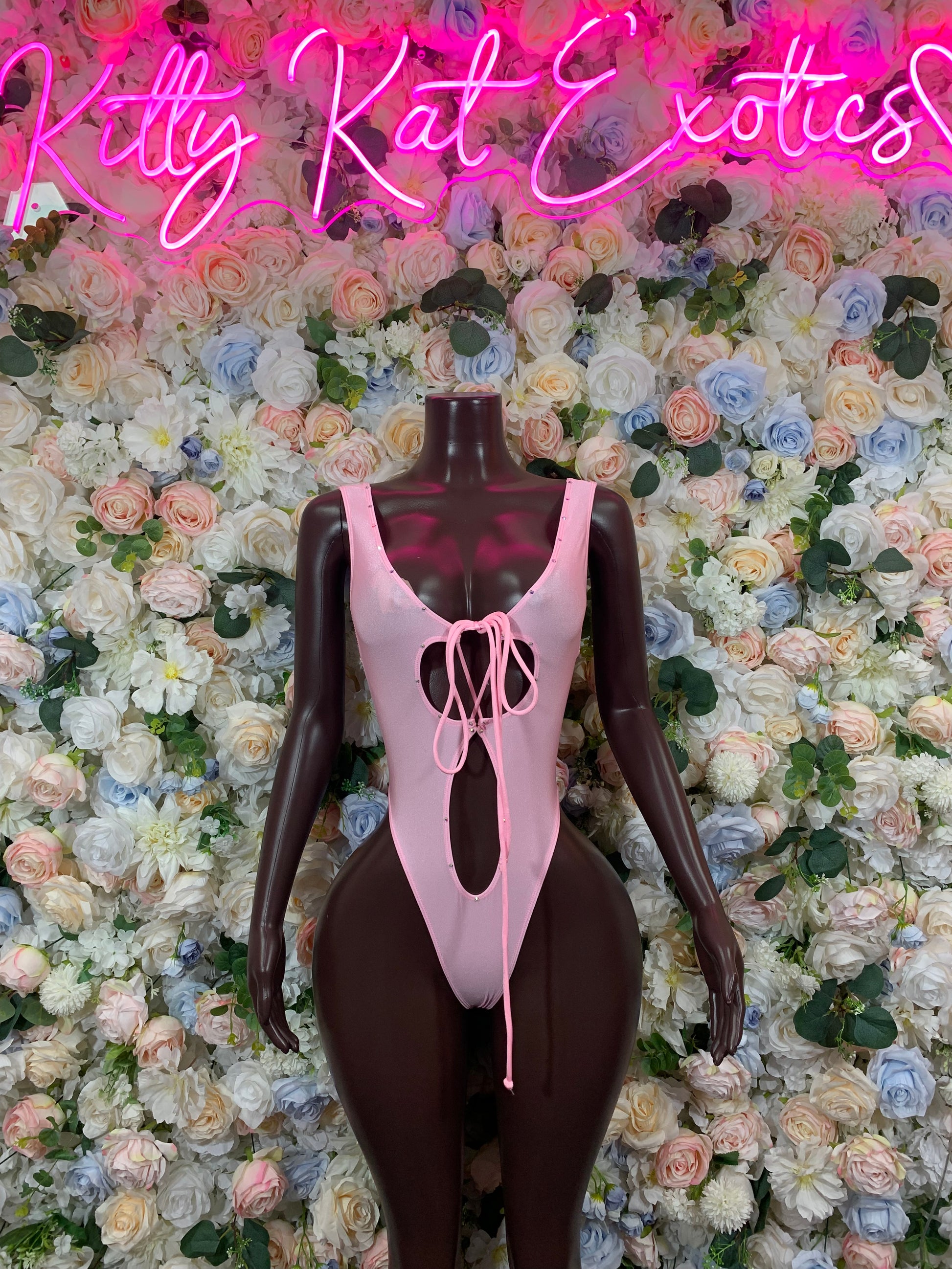 Baby pink one-piece bodysuit with open back V neckline and long ribbon bow detail