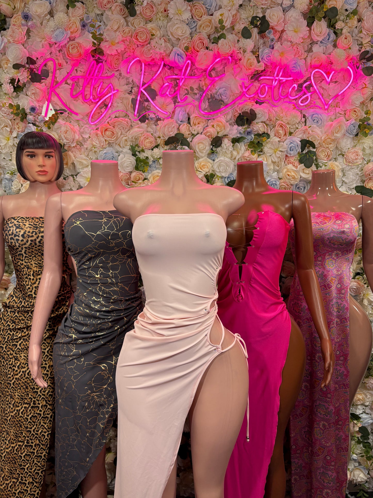 Collection of evening maxi gowns on mannequins, including white and pink strapless styles