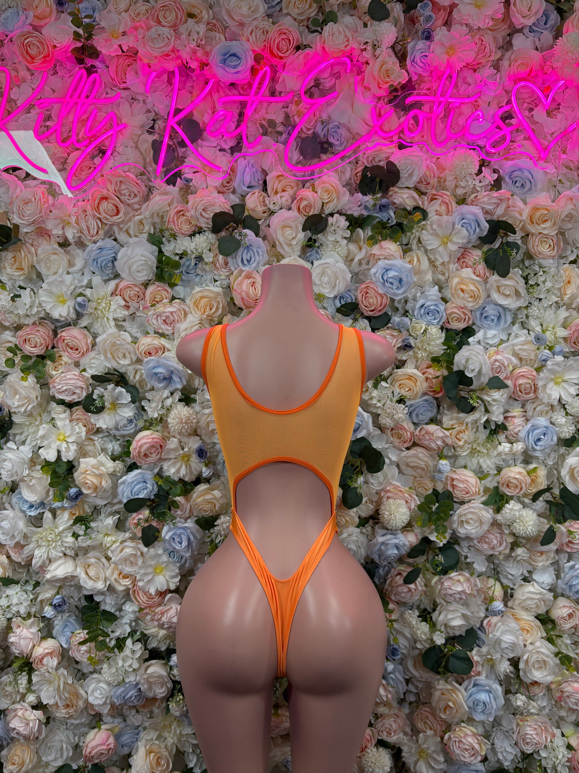 Orange one-piece bodysuit with cross straps and open back on mannequin