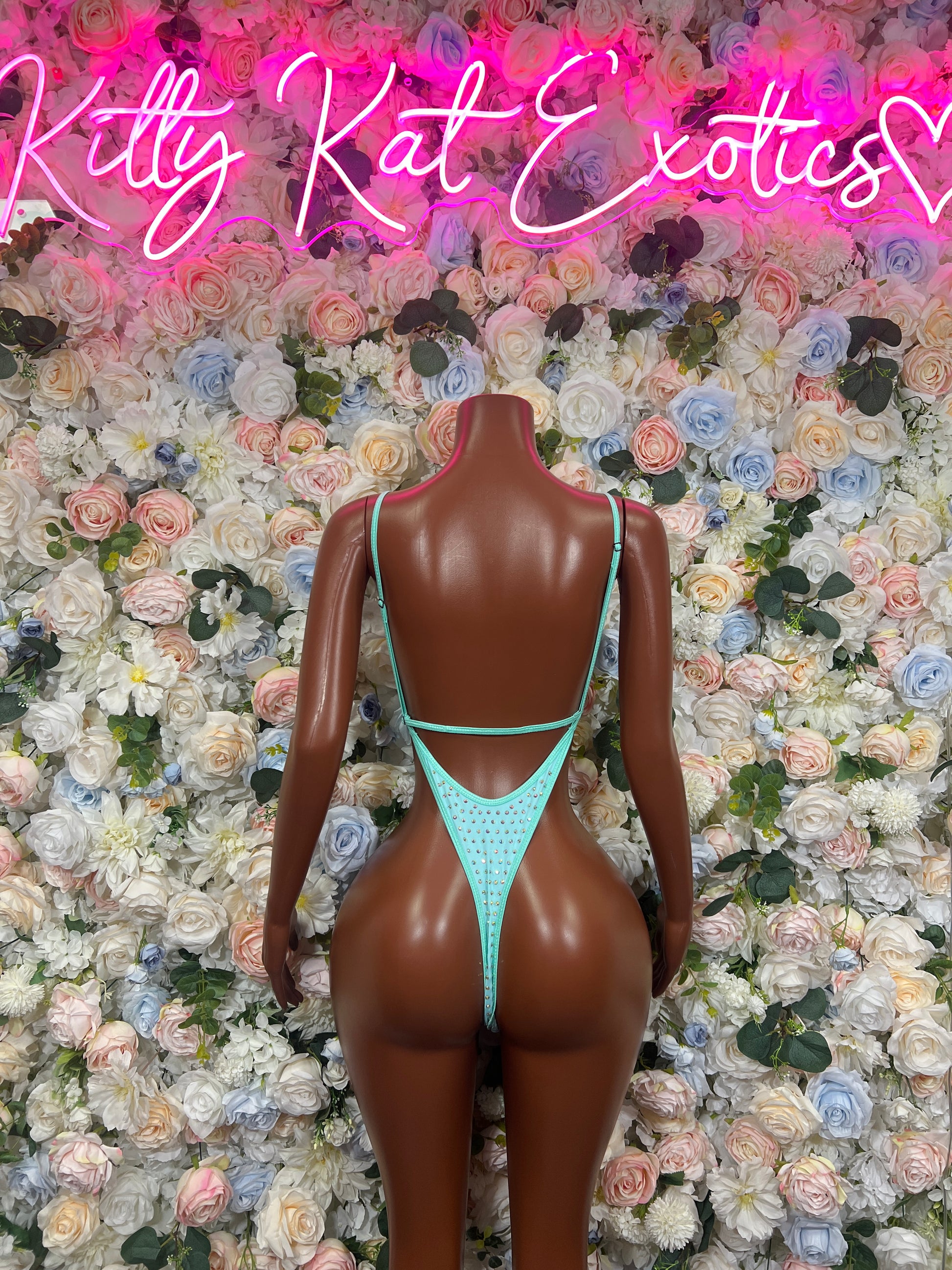 Turquoise rhinestone bodysuit with open V back and thin straps on a mannequin