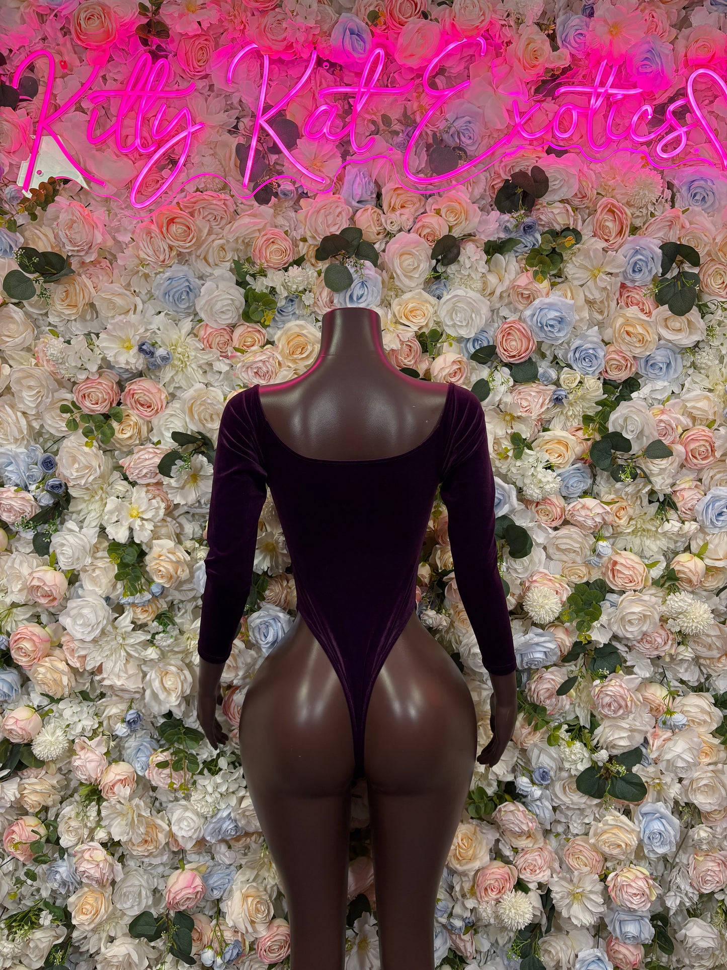 Purple velvet one-piece bodysuit with long sleeves, lace-up front, and high-cut legs