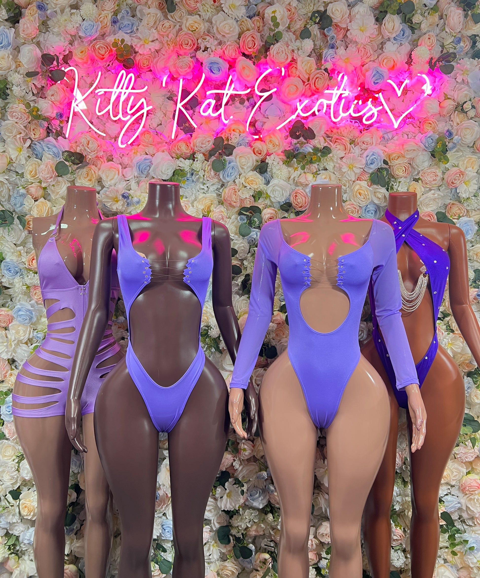 Purple one-piece bodysuits with long sleeves and back tie detail on mannequins