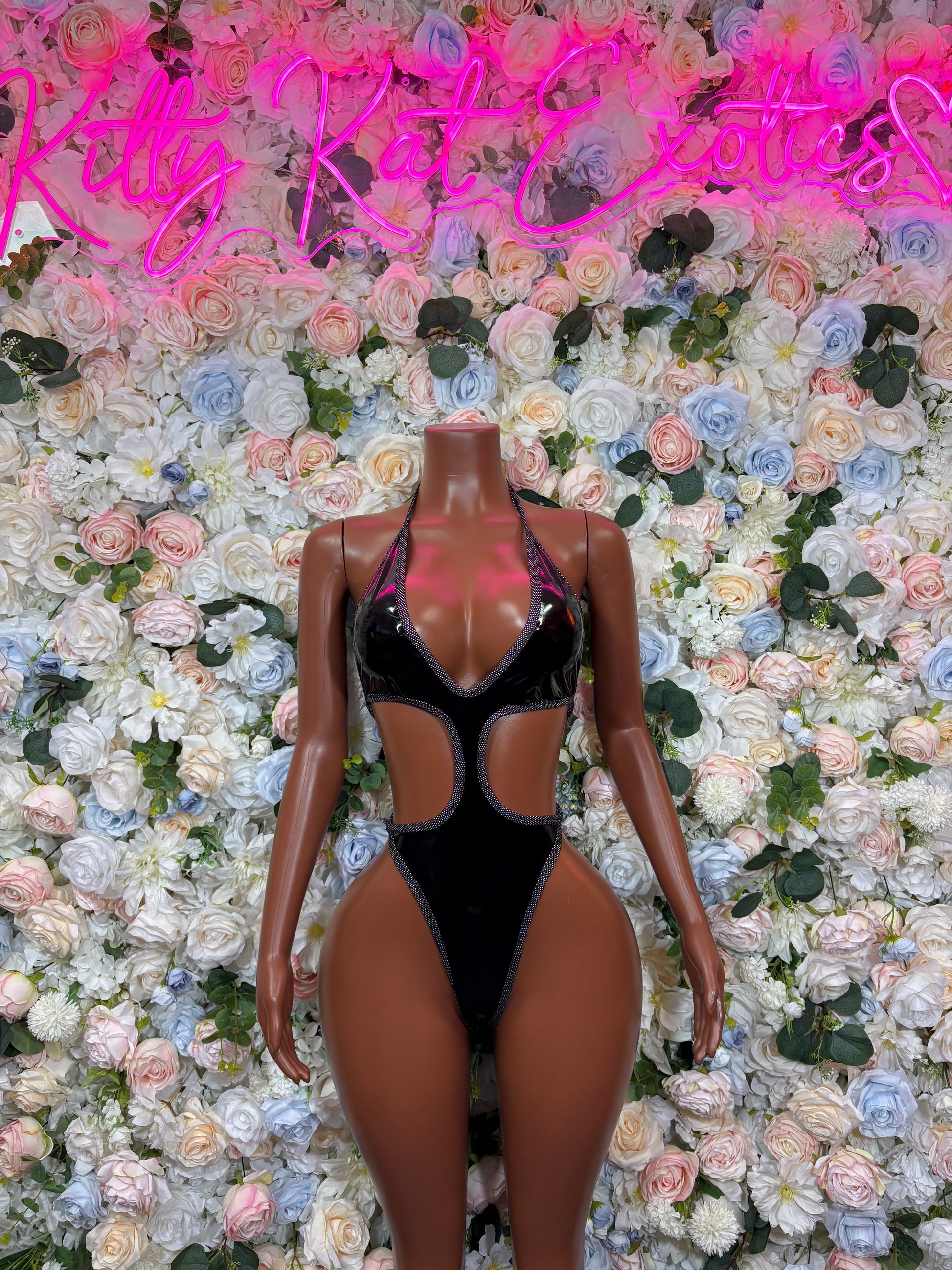 Black latex one-piece bodysuit with V neckline and cutout chest panels