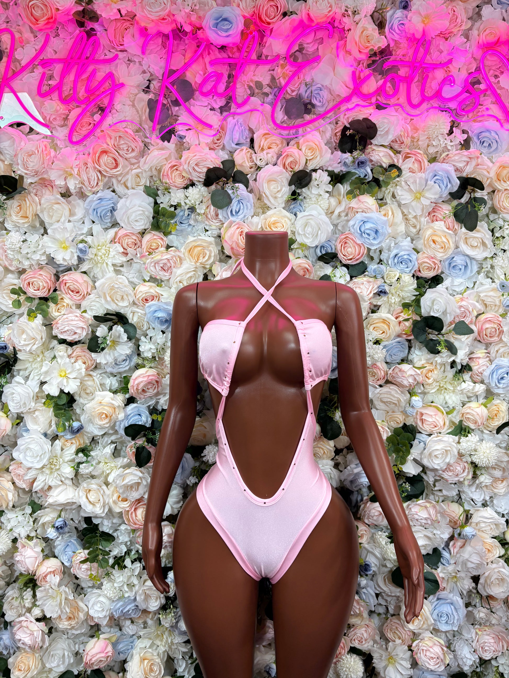 Pink rave bodysuit with plunging front cutout, crisscross straps, cheeky bottom