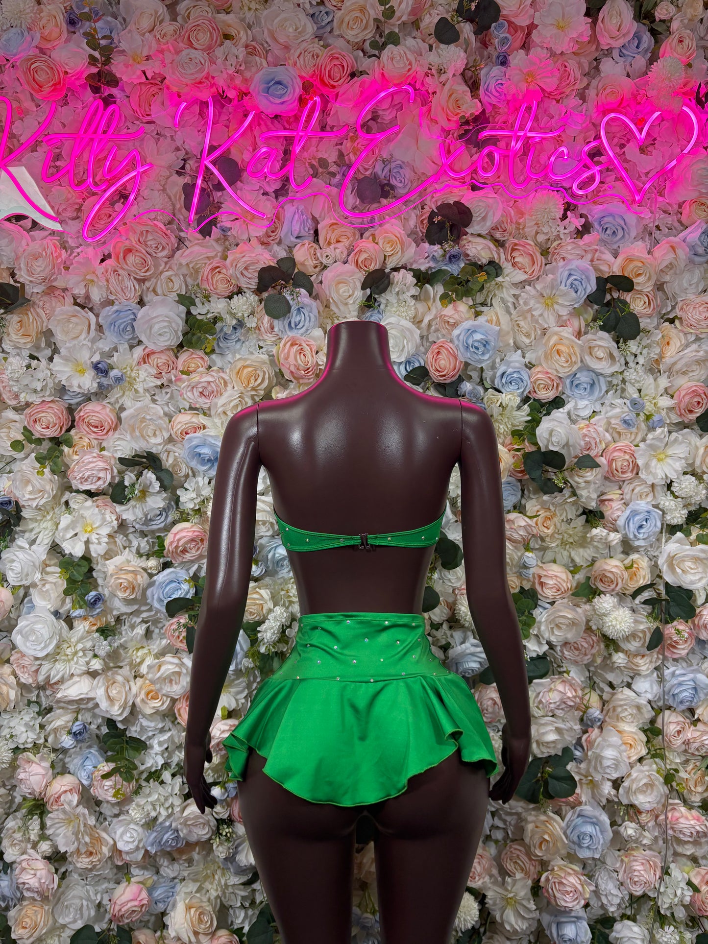Green ruffled mini skirt and bandeau top set on mannequin, back view