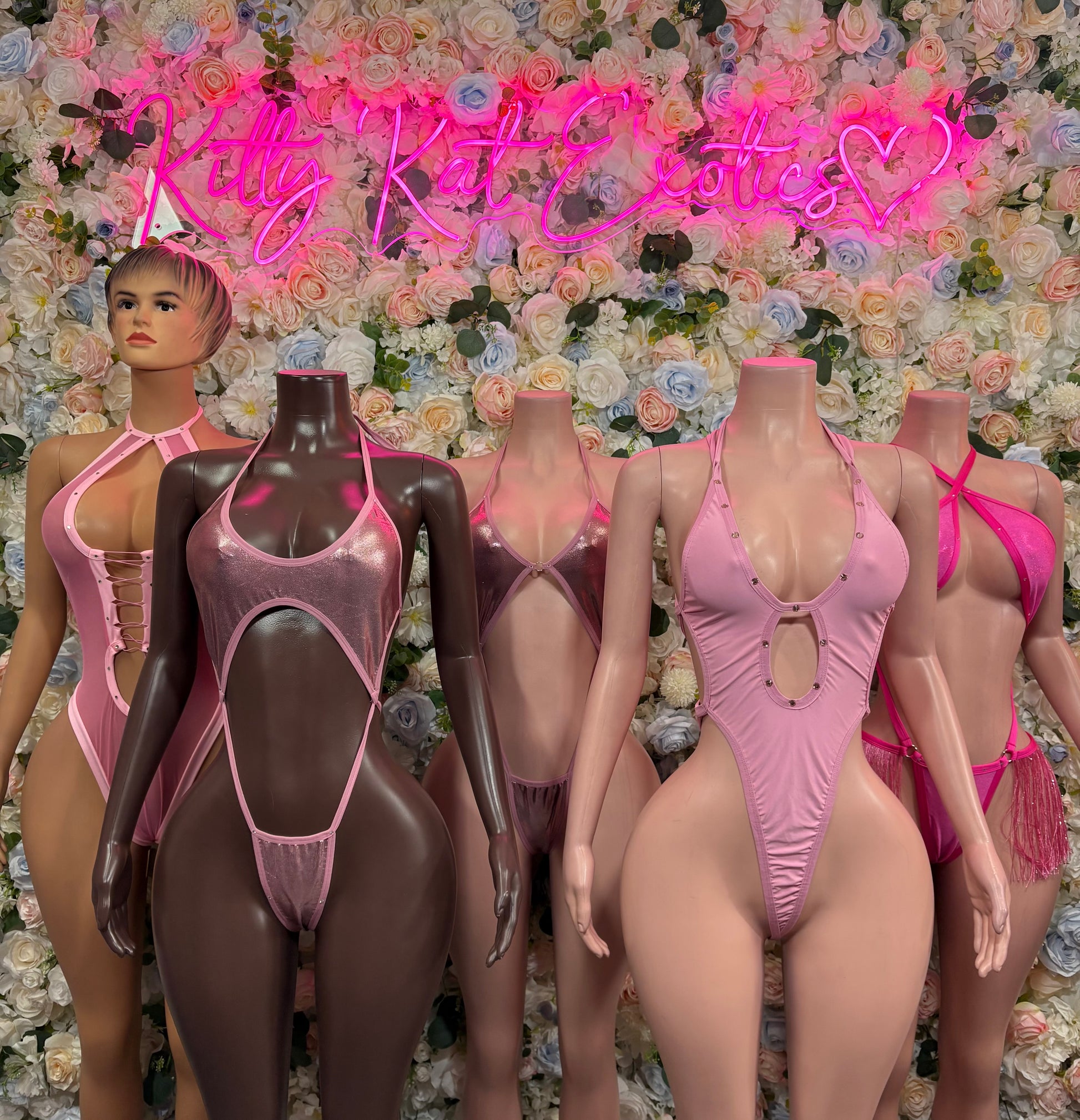 Pink fringe one-piece bodysuits with crisscross open-back straps on mannequins